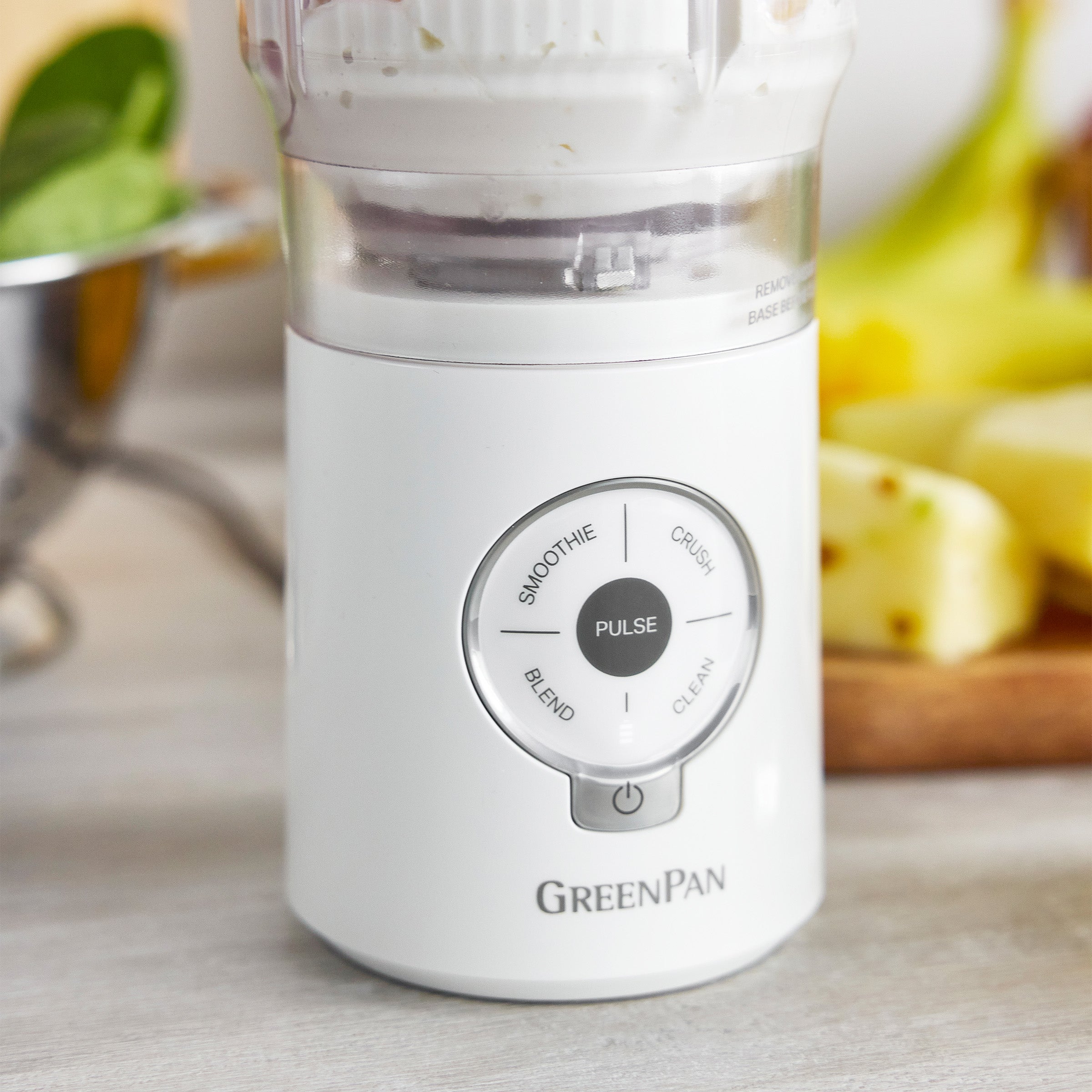 White blender with control panel on a kitchen counter, surrounded by fruits.