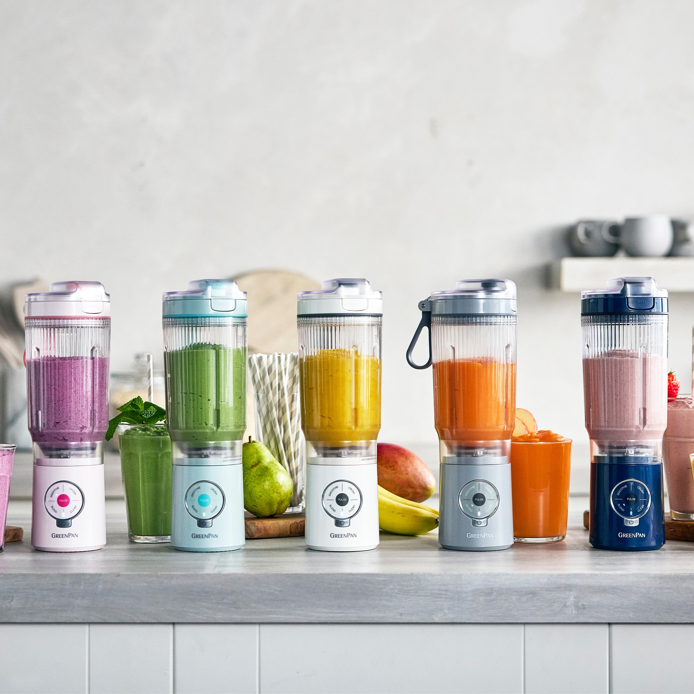 Five portable blenders with colorful drinks on a kitchen counter.