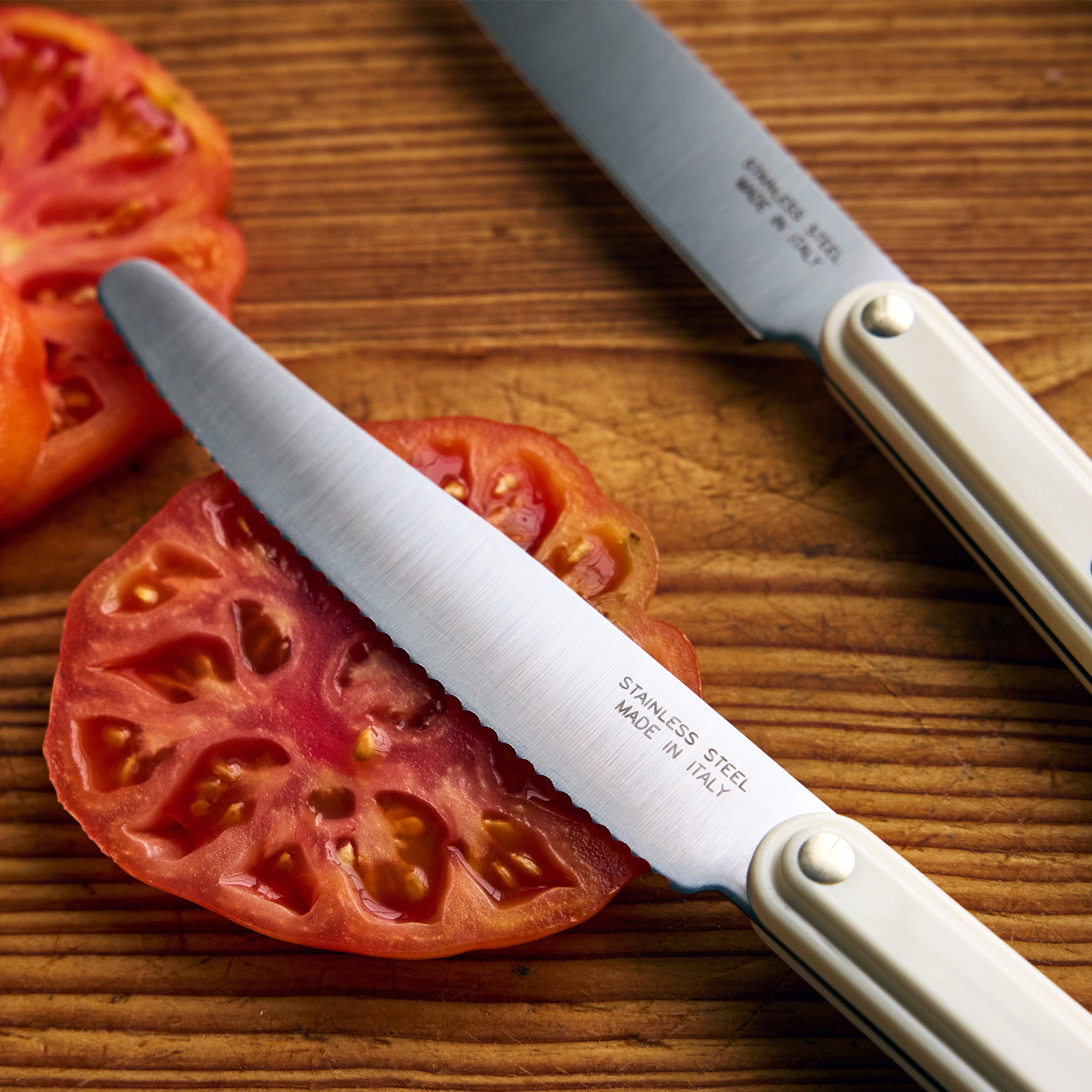 Sliced tomatoes on a wooden cutting board with a knife