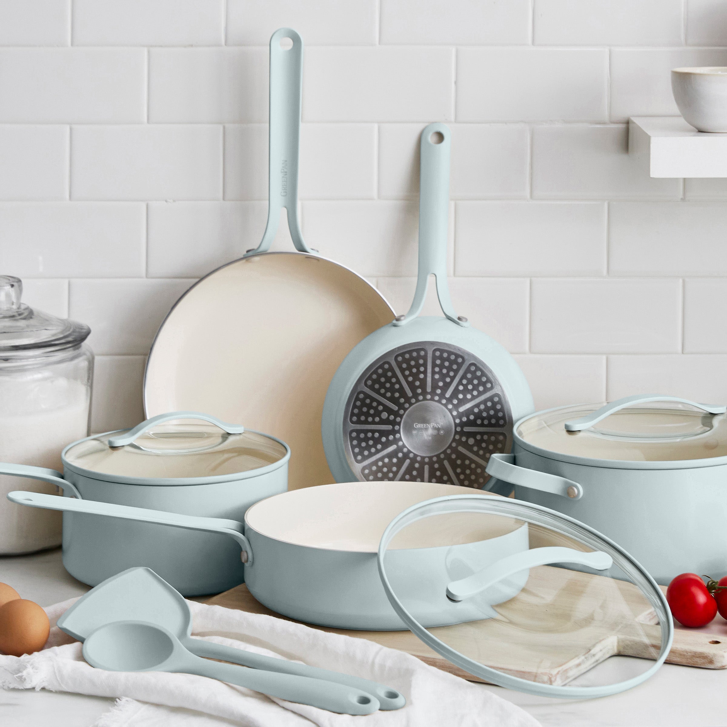 Set of light blue cookware including pots, pans, and lids on a kitchen counter.