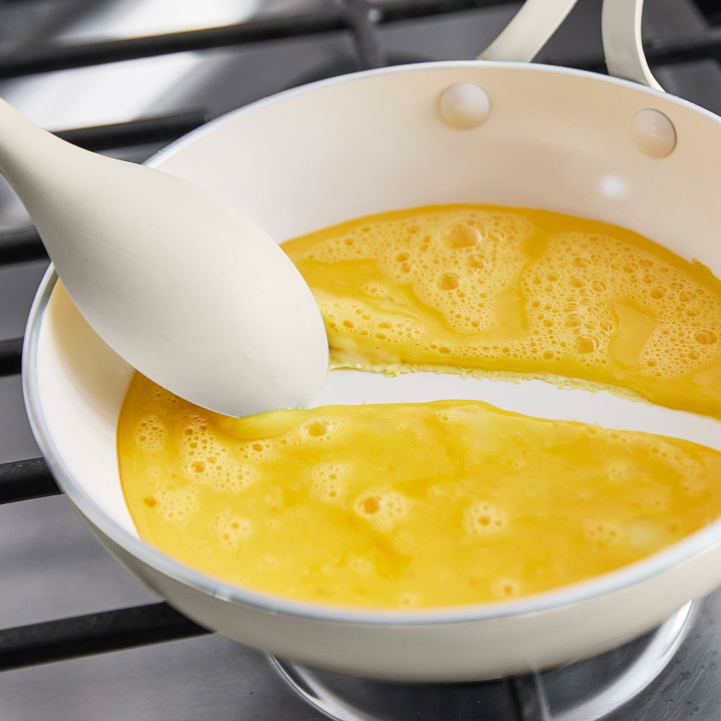 Frying pan with scrambled eggs and a spatula on a stove