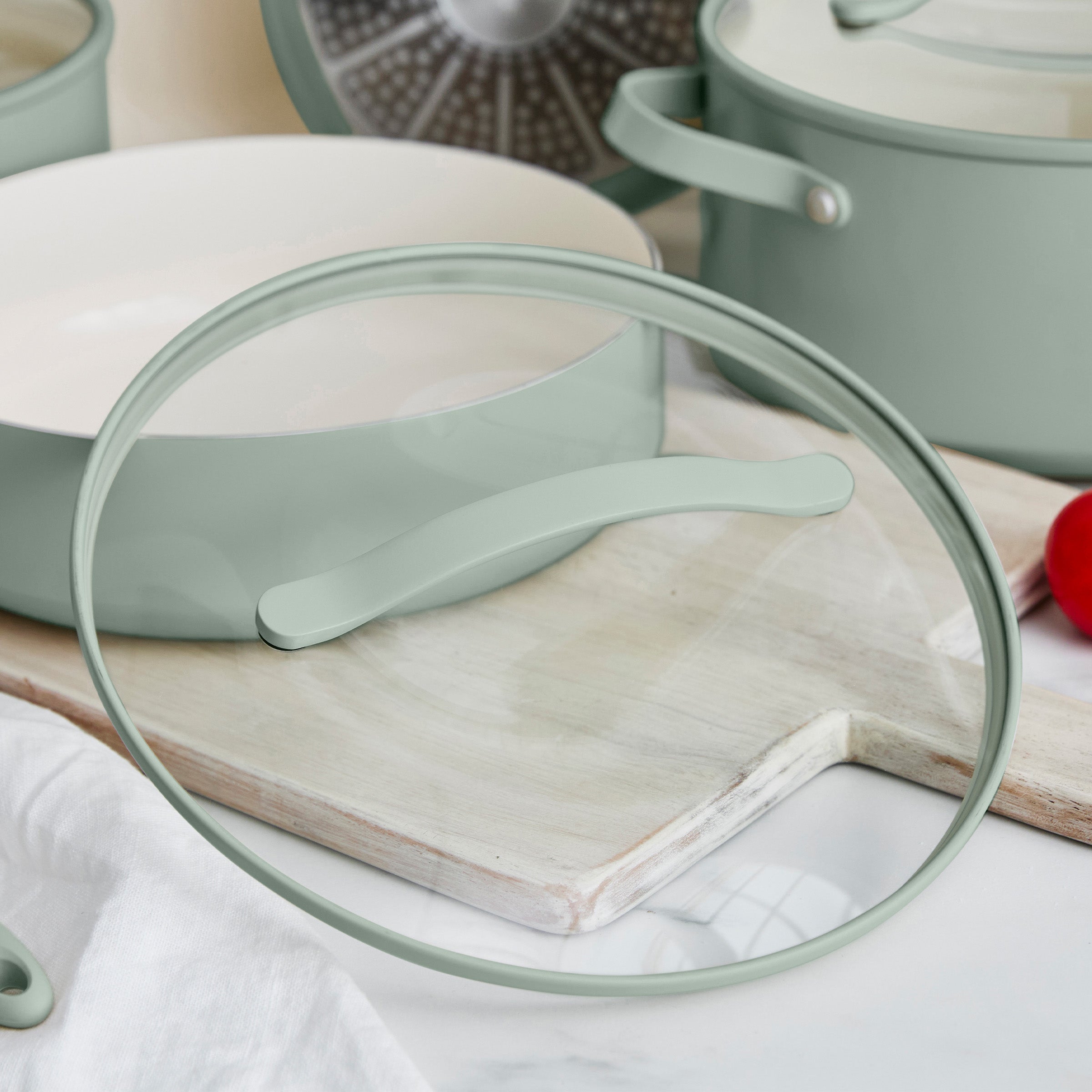 Green pan with a glass lid on a wooden surface