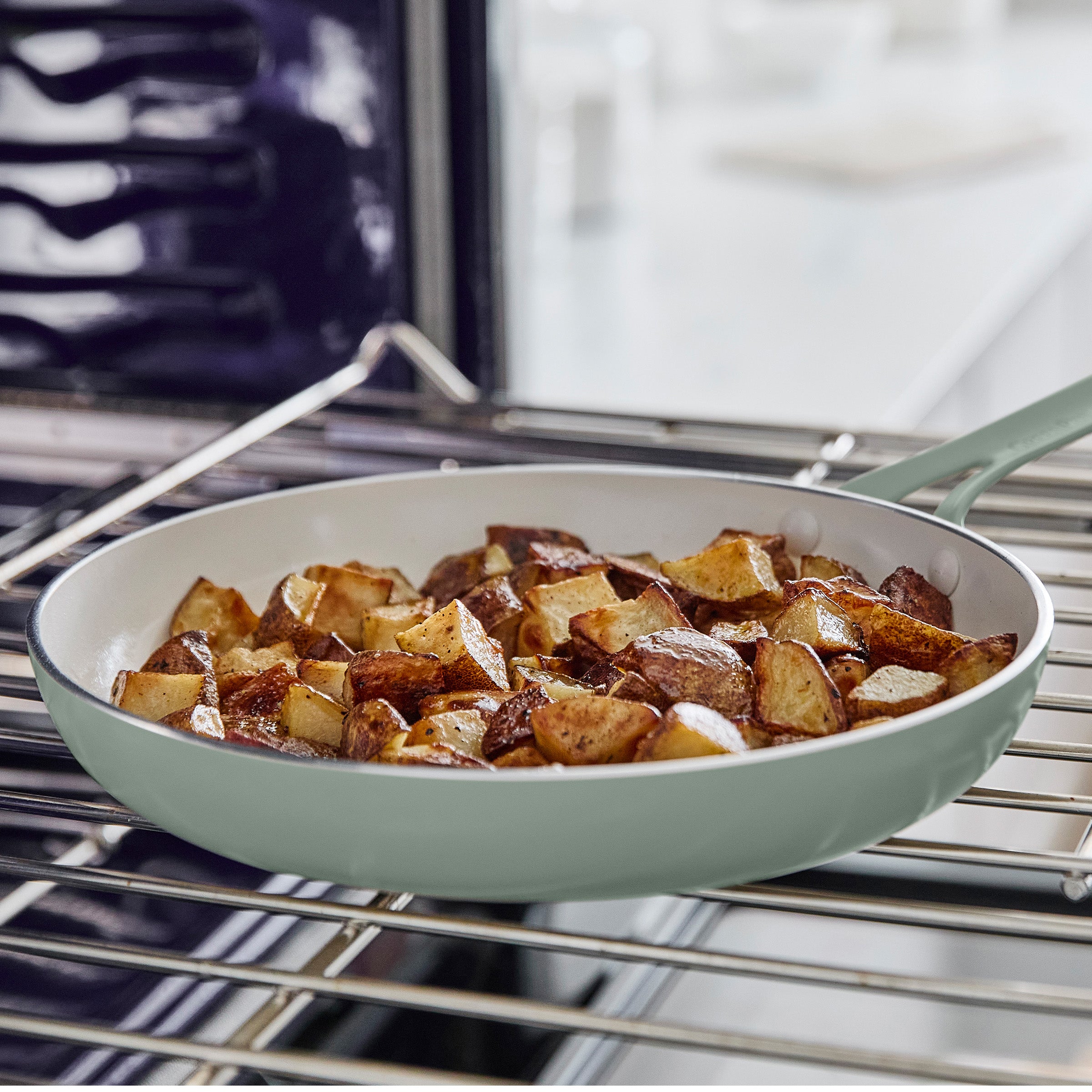 Green frying pan with roasted potatoes on an oven rack