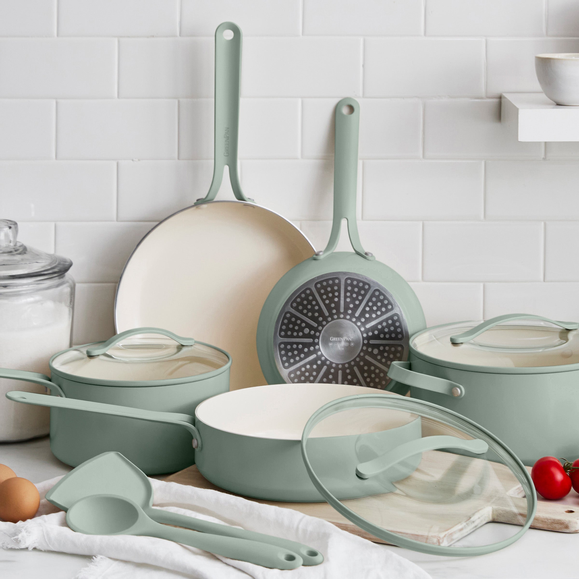 Set of green cookware including pots, pans, and lids on a kitchen counter.