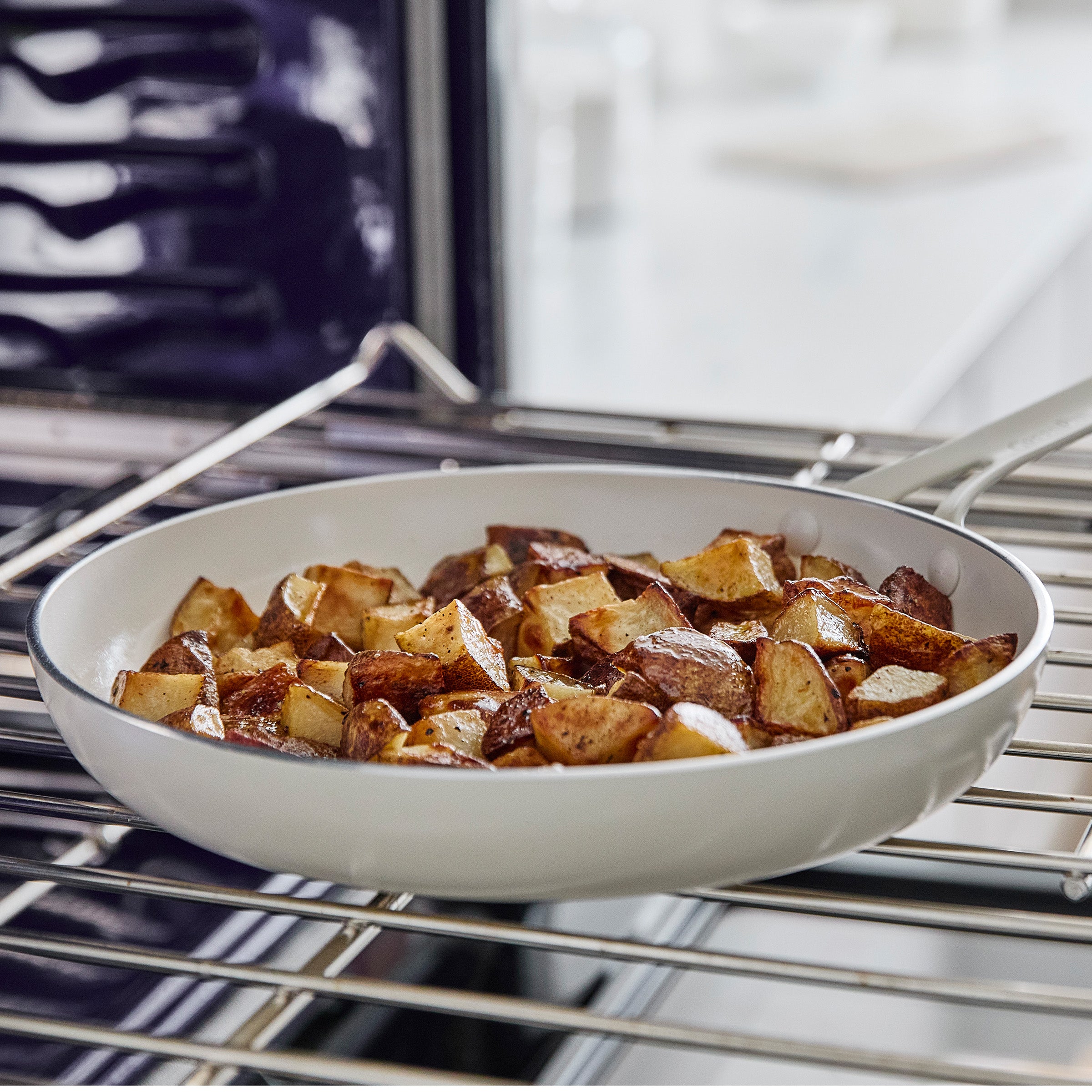 White frypan with roasted potatoes on an oven rack