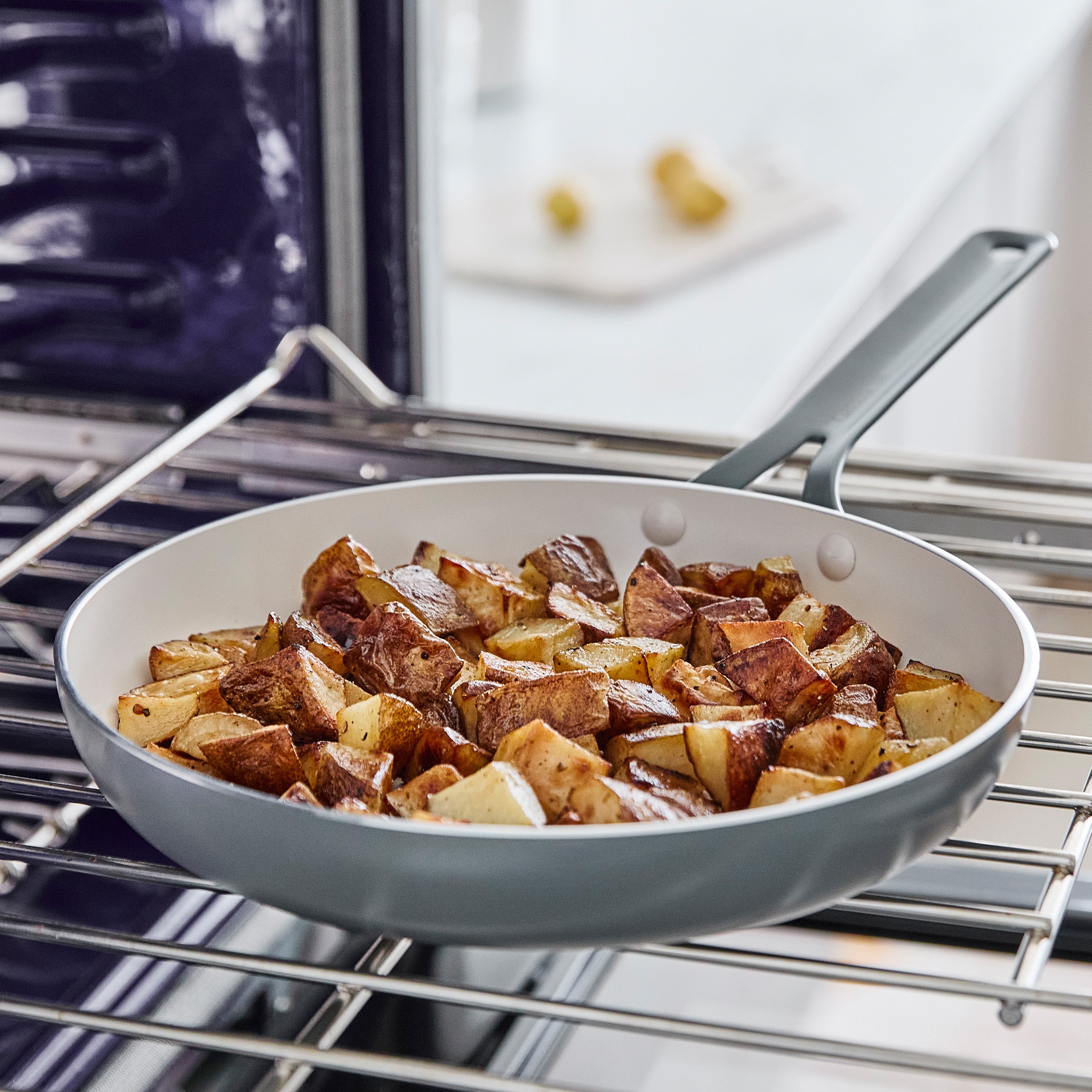 Gray frying pan with roasted potatoes on a metal oven rack.