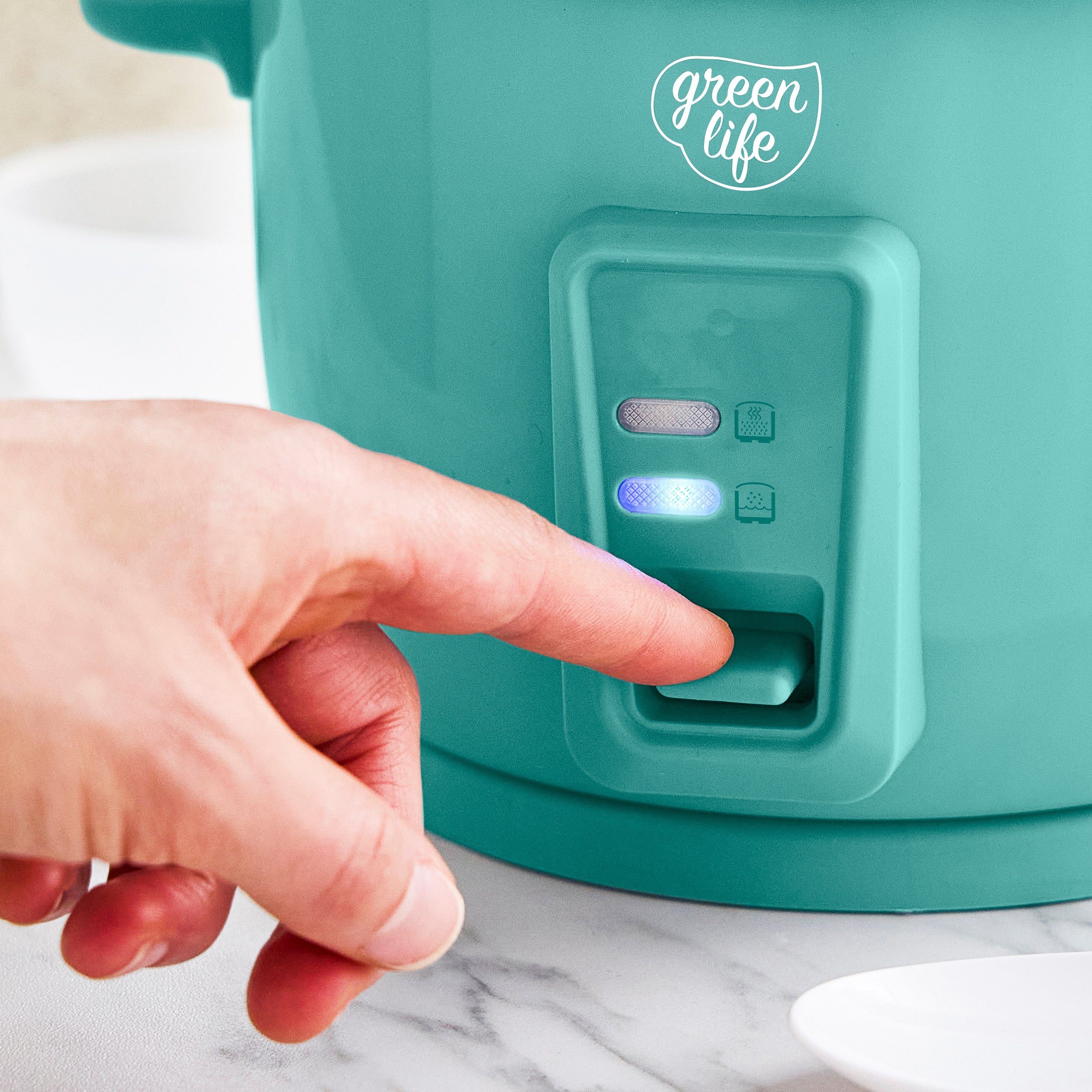 Turquise appliance with 'green life' branding, hand pressing a button.
