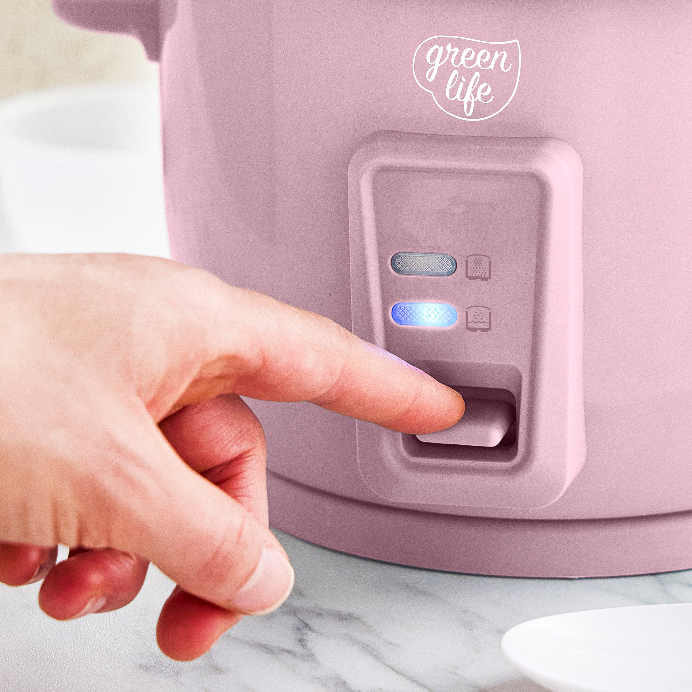 Person pressing a button on a pink appliance with 'green life' branding.