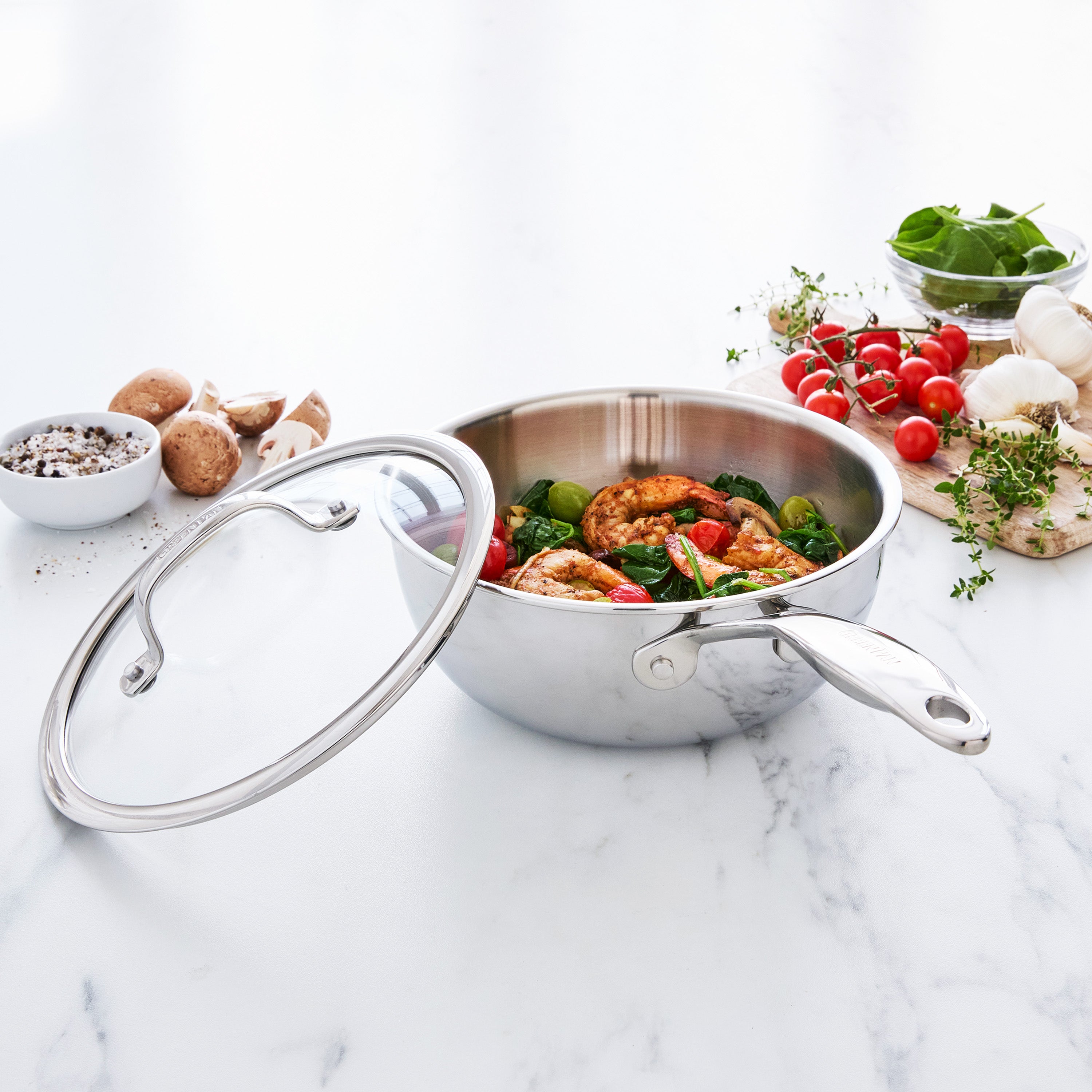 Stainless steel chef's pan with food on a marble surface