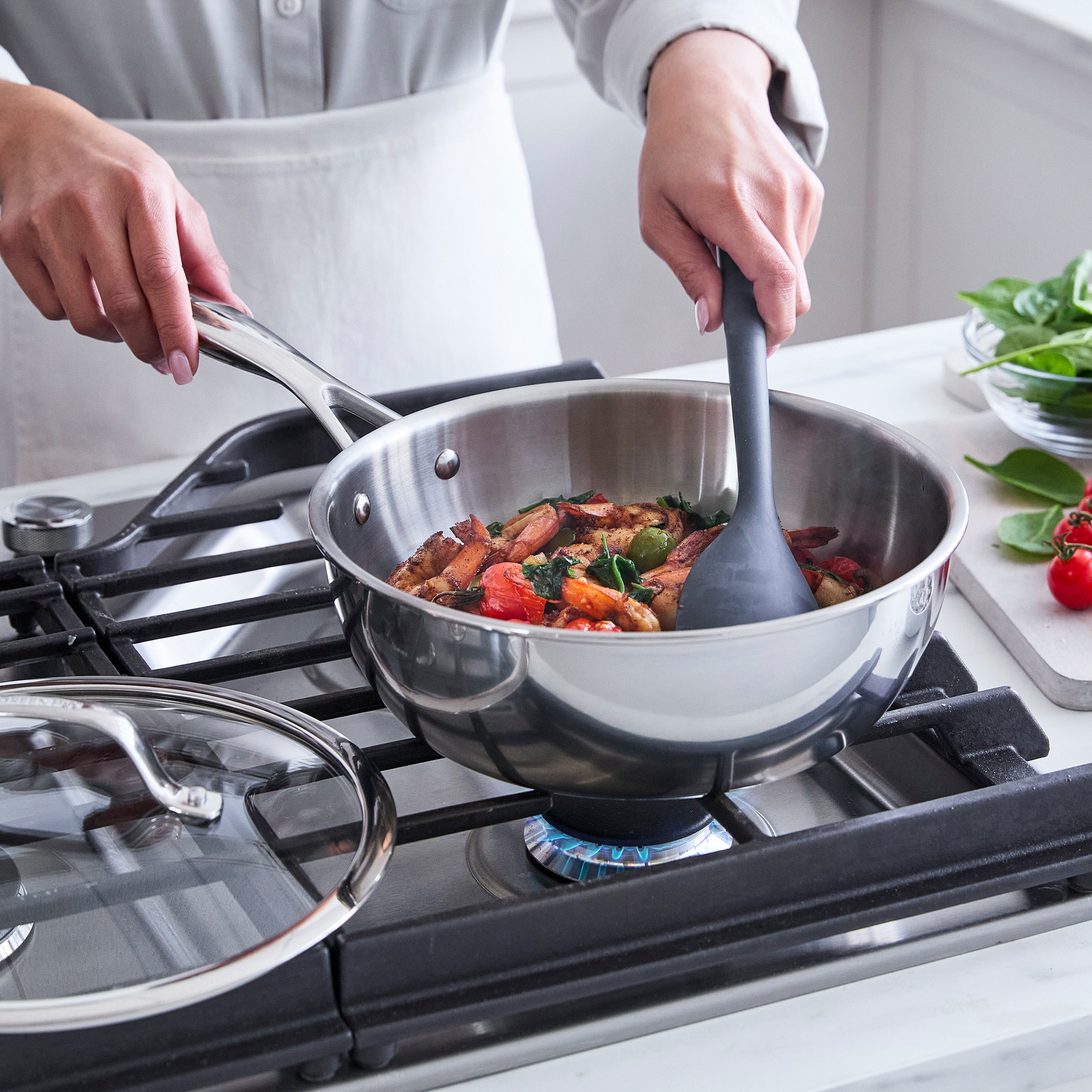 Person cooking vegetables in a stainless steel chef's pan on a stove