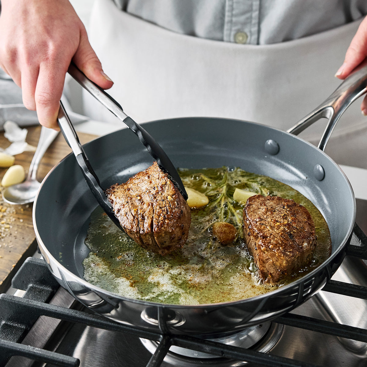 Two beef fillets searing with butter and herbs in a Valencia Pro Stainless Steel 9-piece cookware pan.