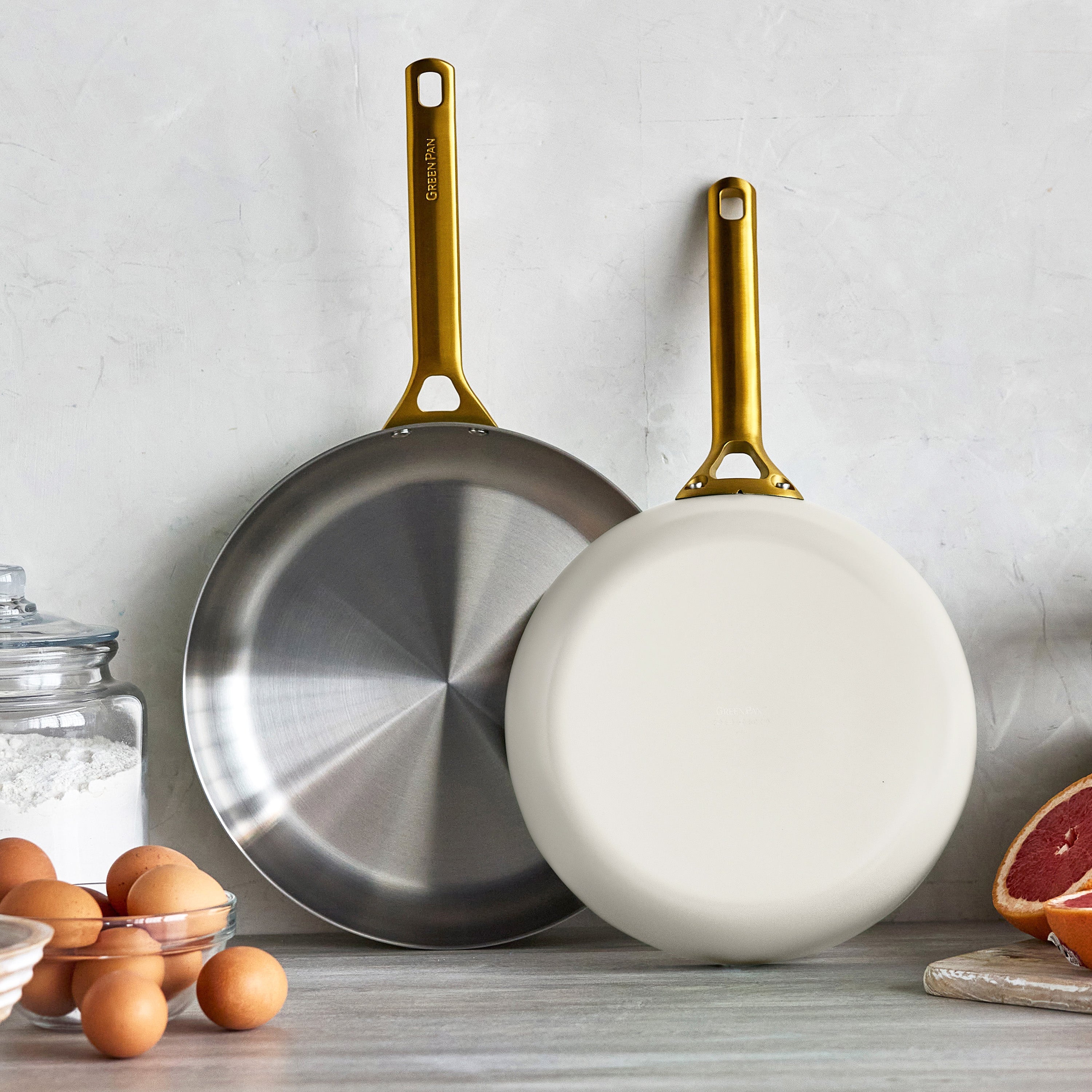 Two frying pans with gold handles on a kitchen counter.