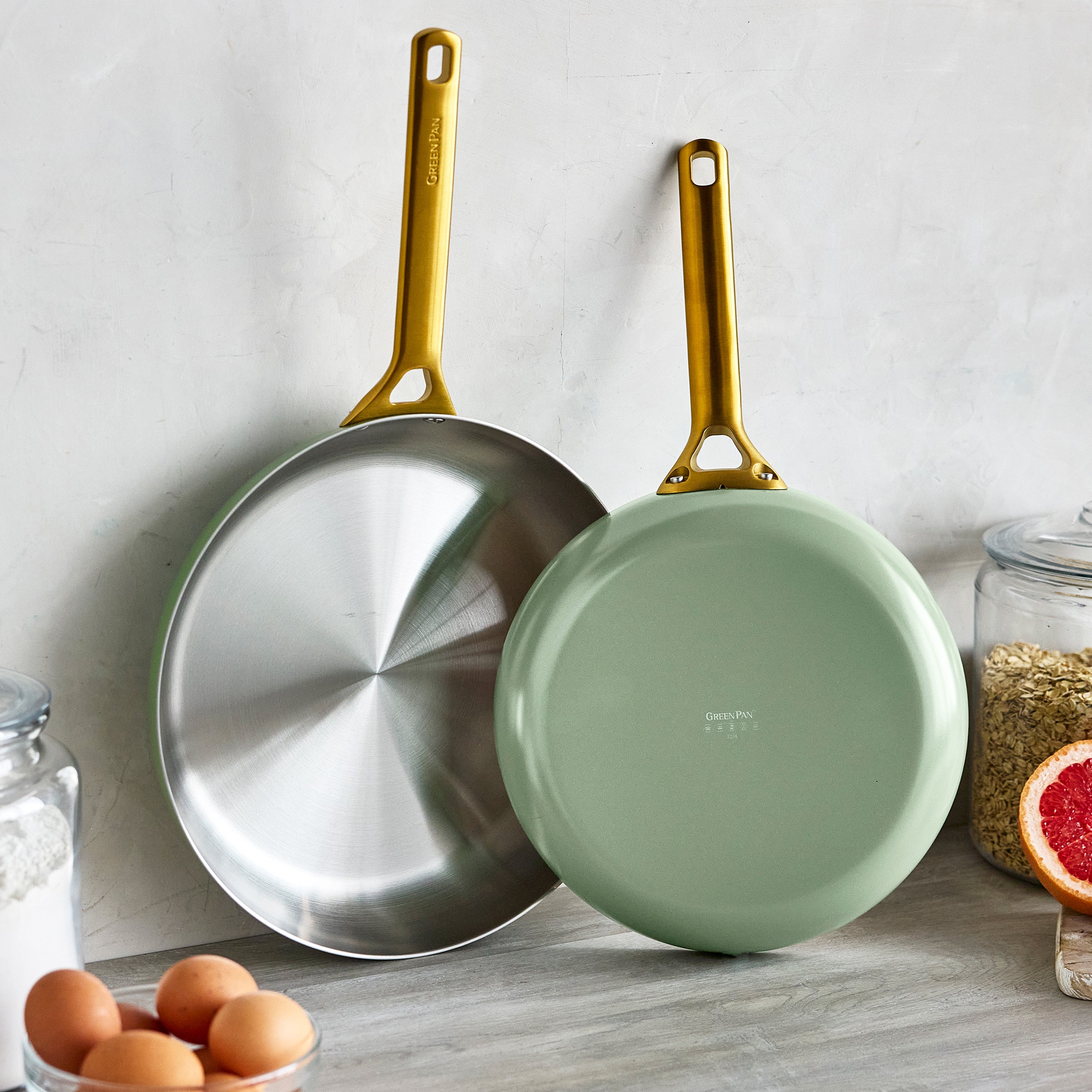 Two frying pans with gold handles on a kitchen counter.