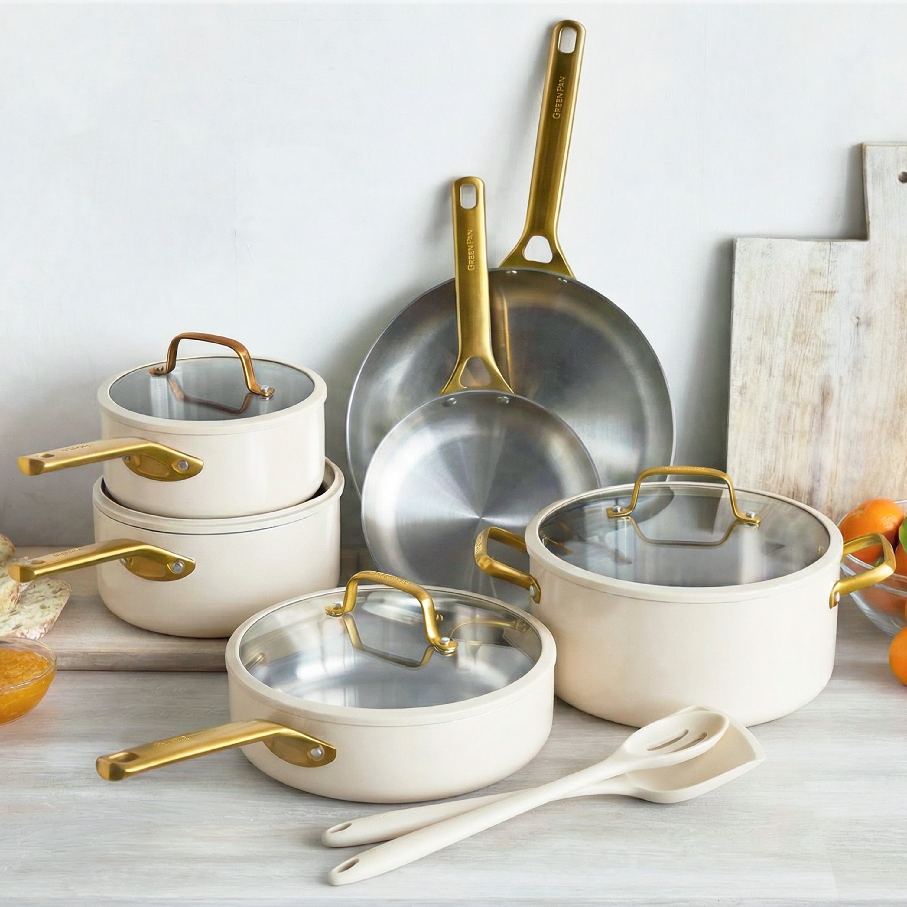 Set of cookware with gold handles on a light wooden surface.