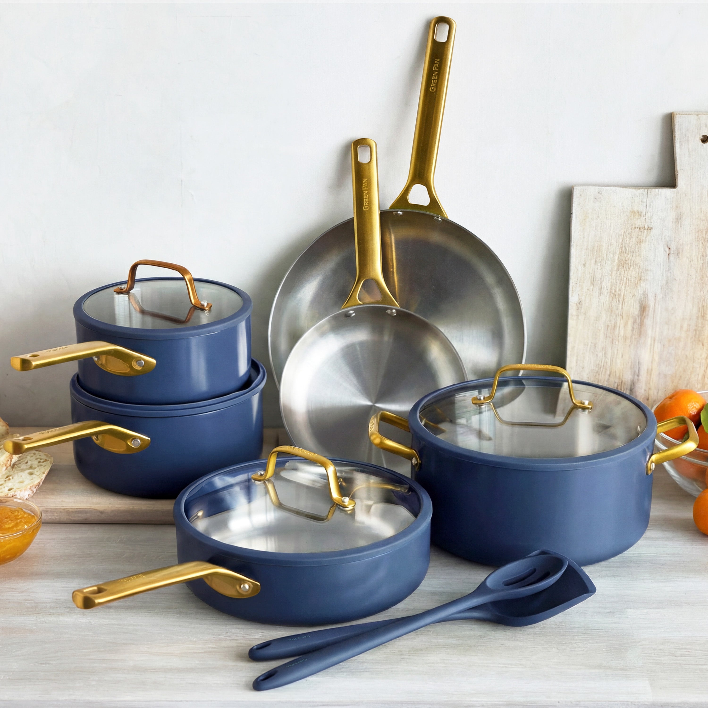 Set of blue cookware with gold handles on a light wooden surface.