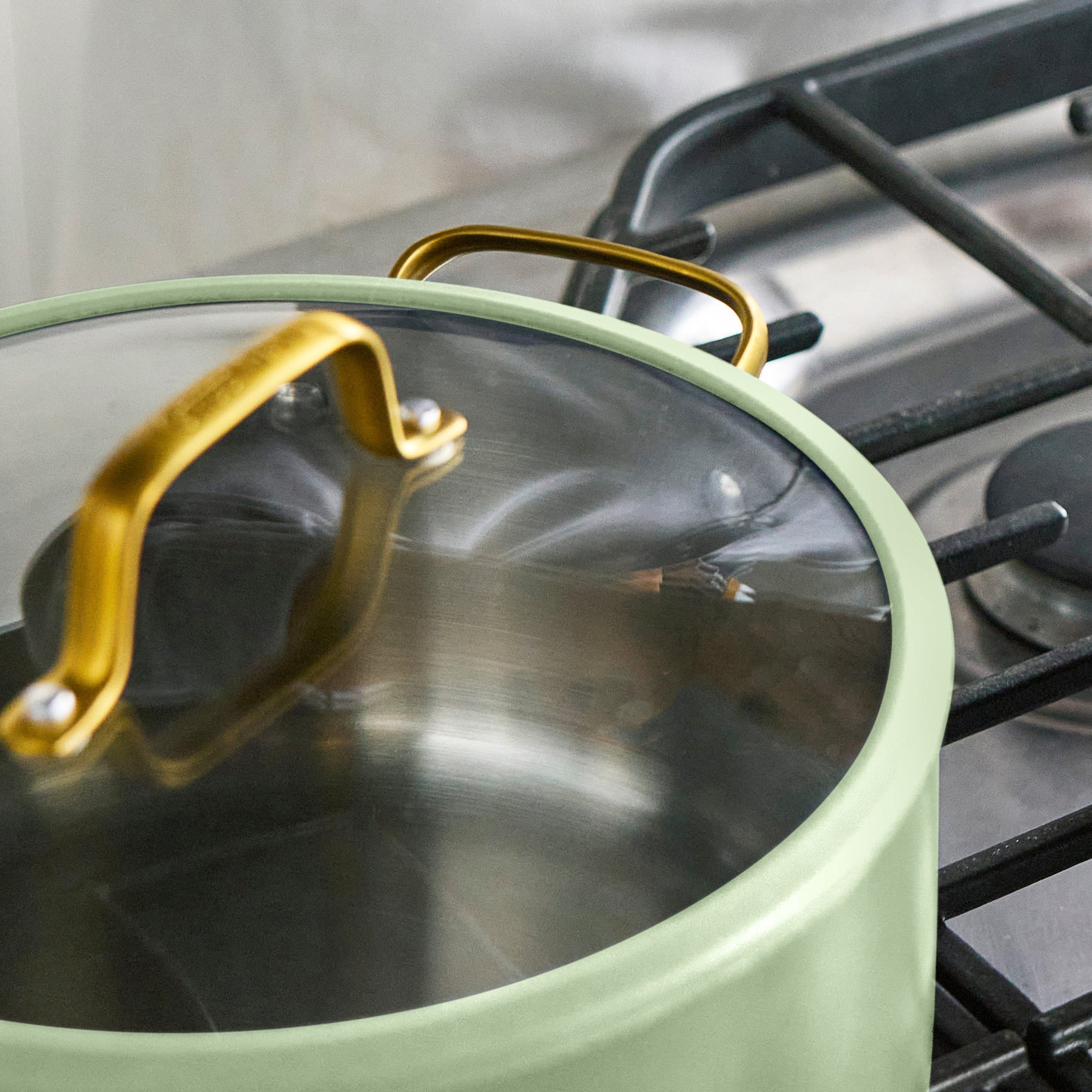 Green pot with a gold handle on a stove