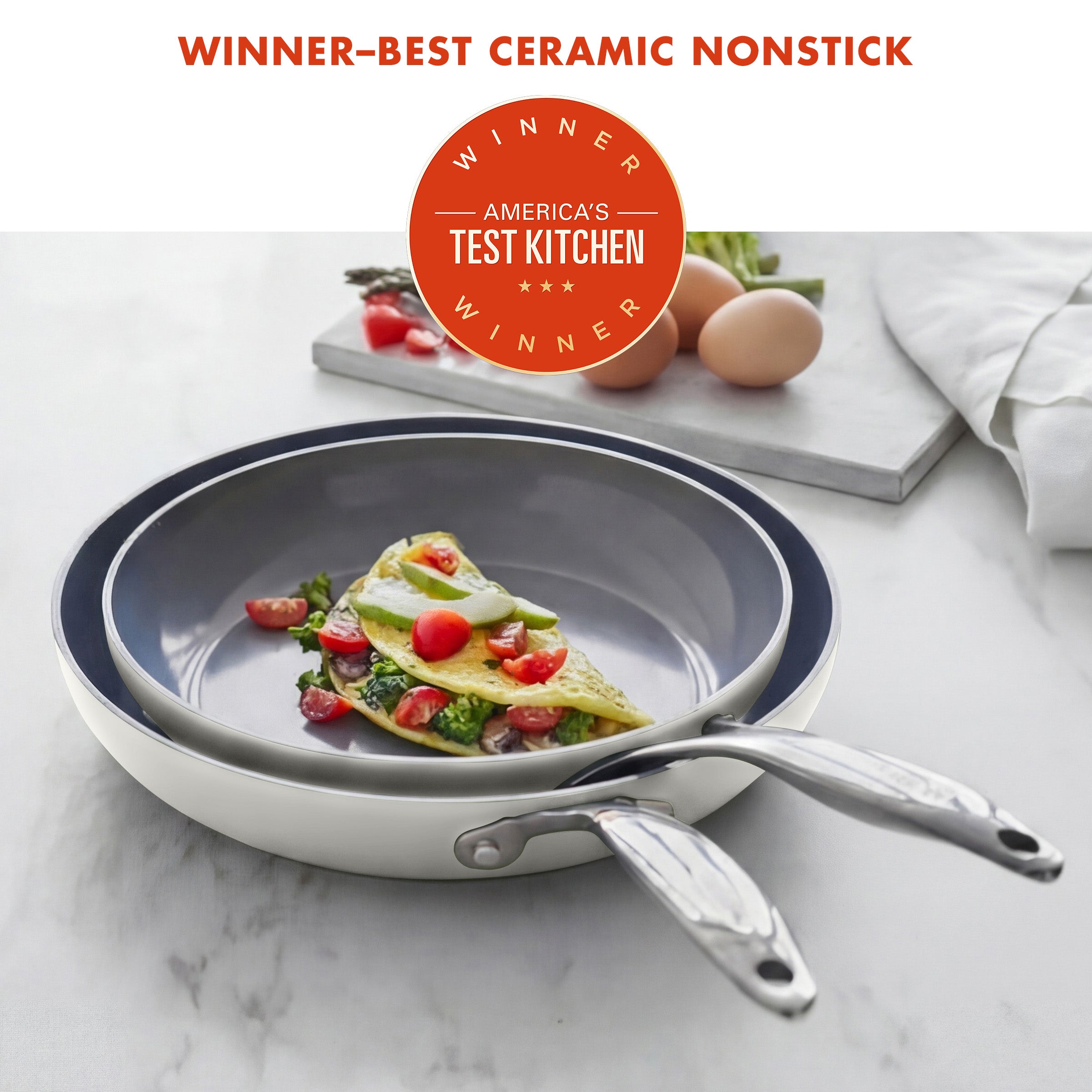 Ceramic nonstick frying pan with omelette on a marble surface, featuring America's Test Kitchen award.