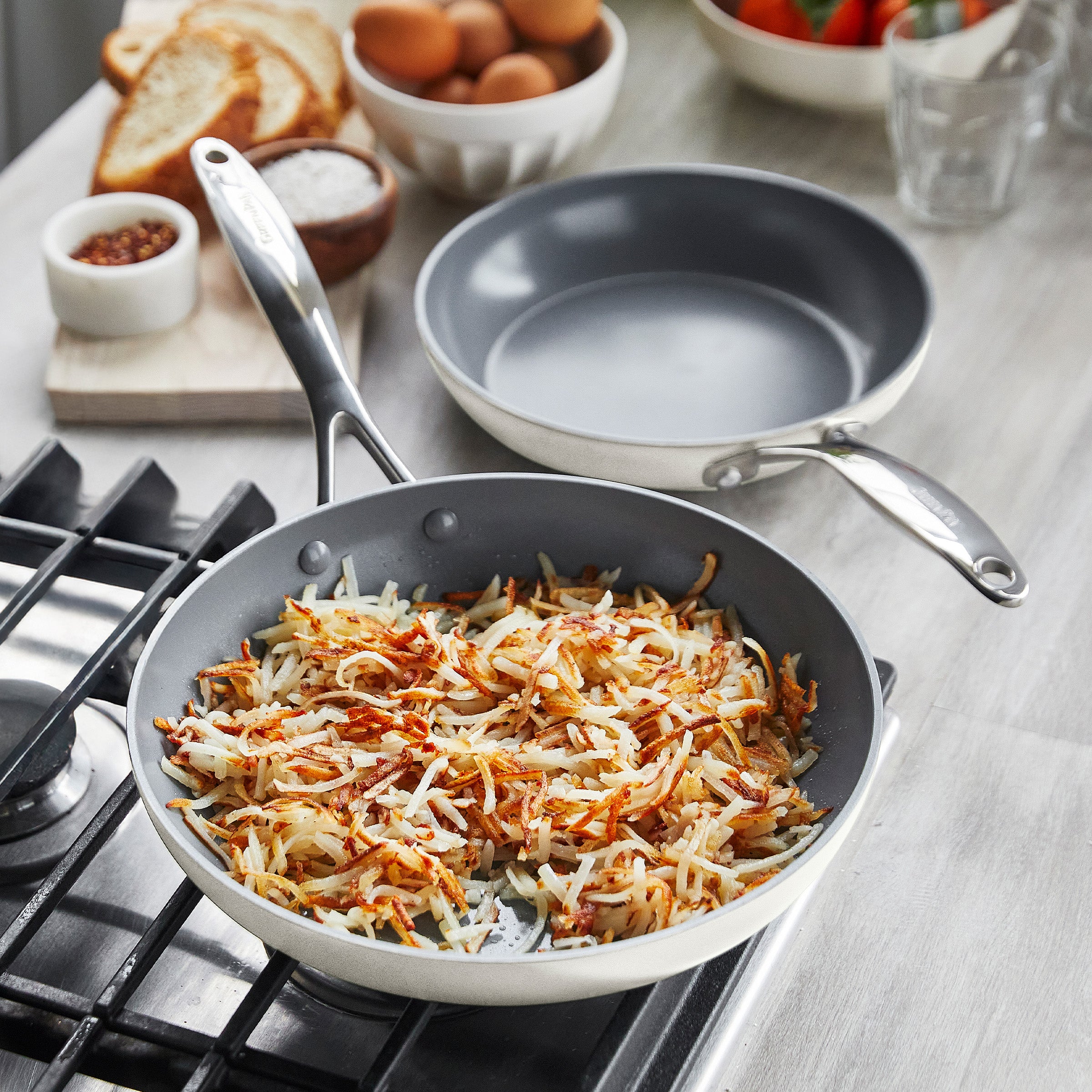 Cooking hashbrowns in a cream frypan on a gas stove