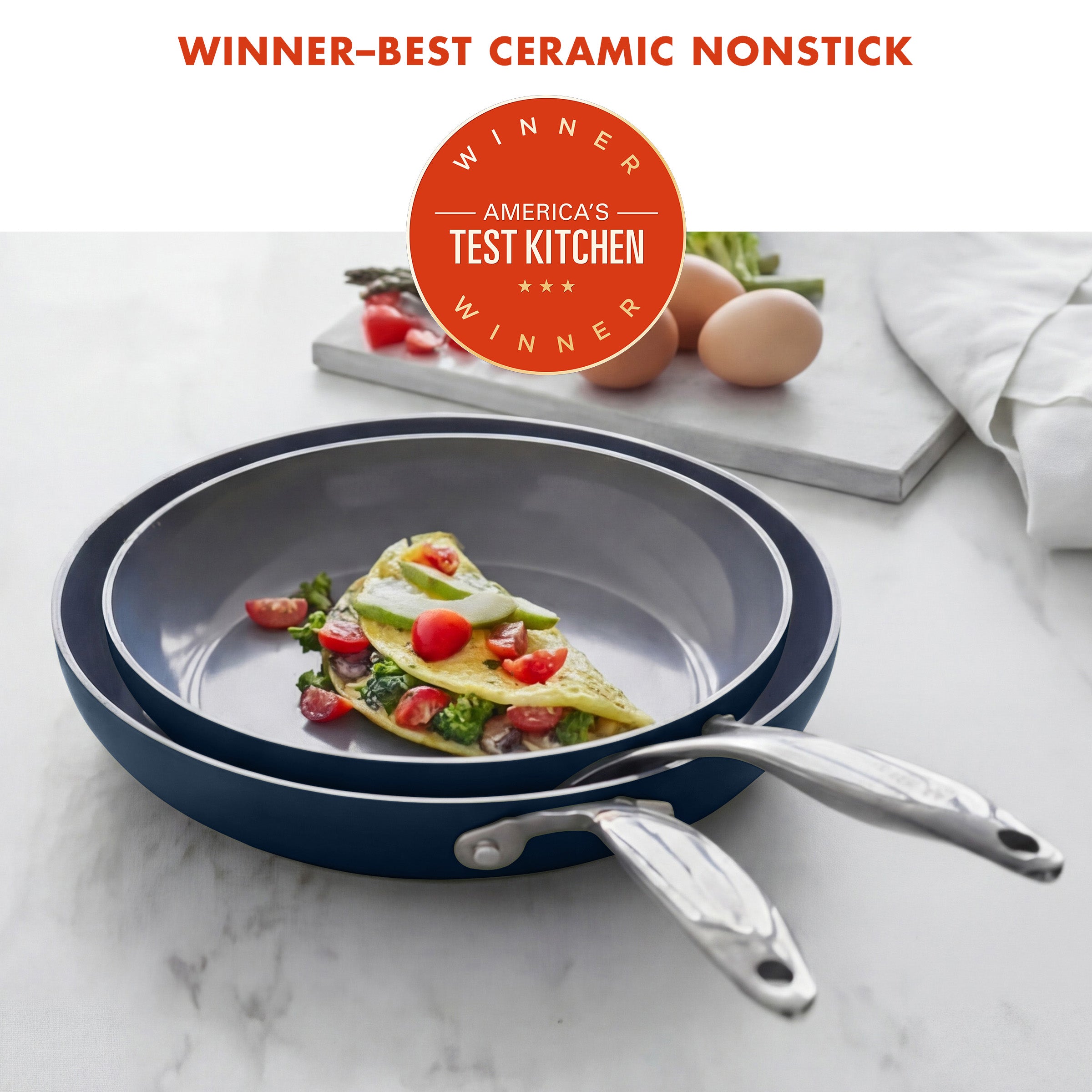 Ceramic nonstick frying pan with omelette on a marble surface, featuring America's Test Kitchen award.