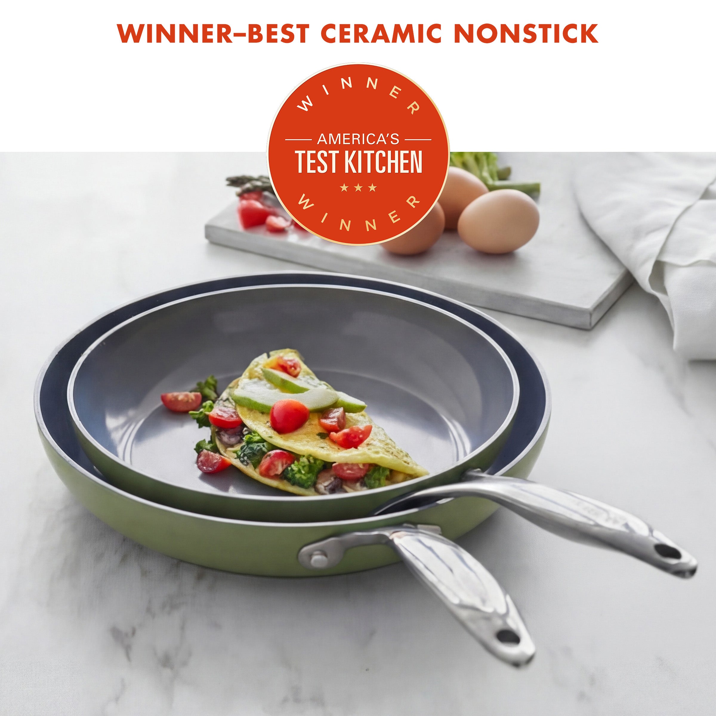 Ceramic nonstick frying pan with omelette on a marble surface, featuring America's Test Kitchen award.