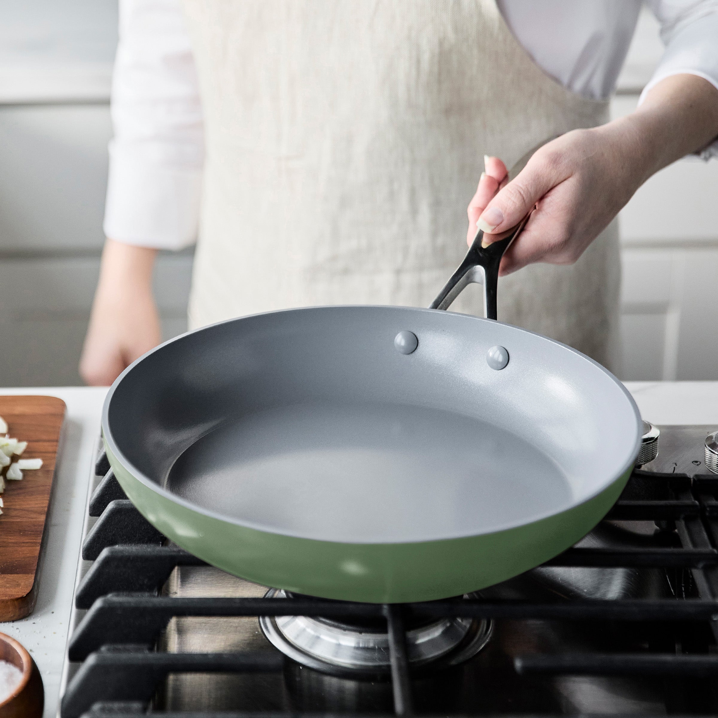 Person holding a blue frying pan over a gas stove