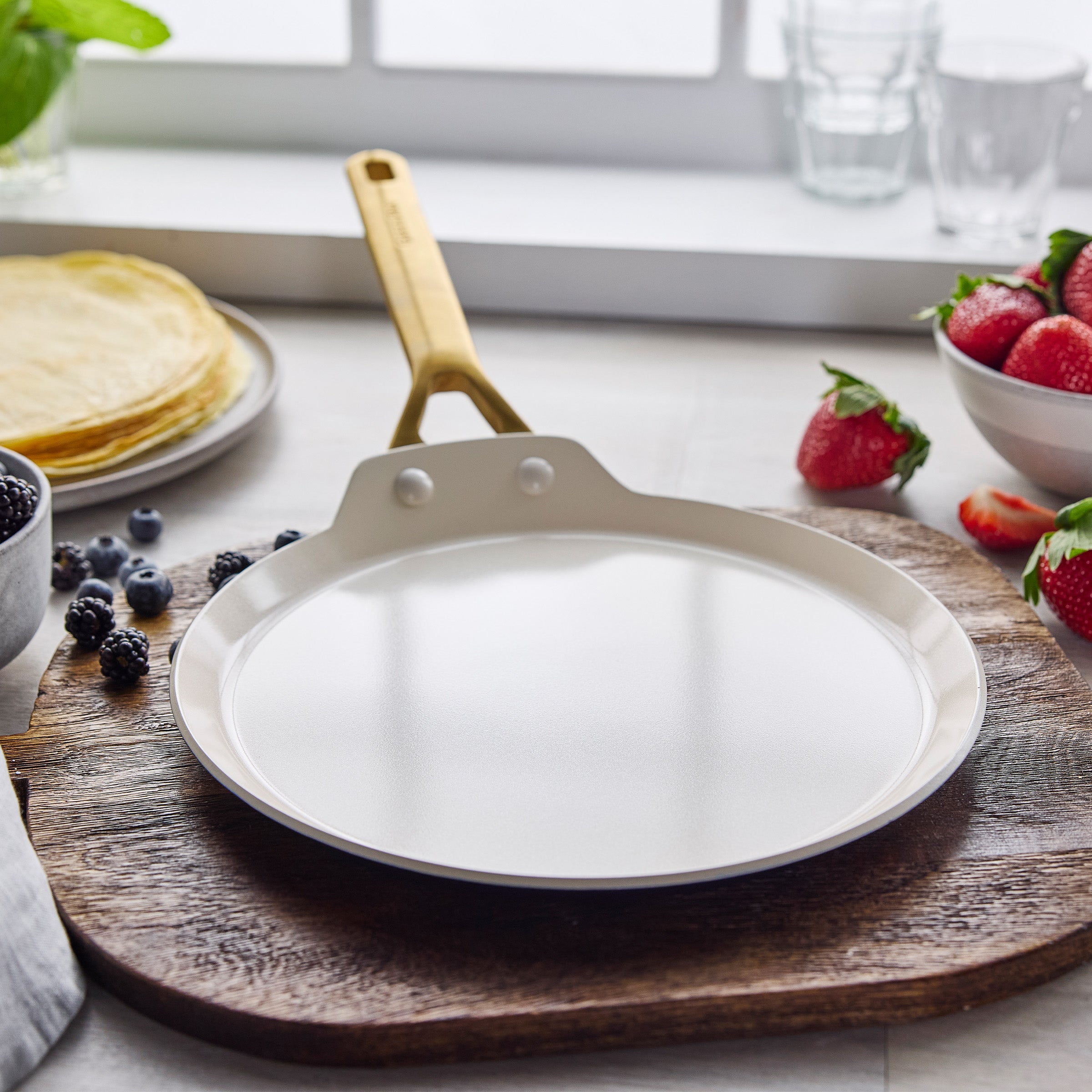 Crepe pan on wooden board with berries the background