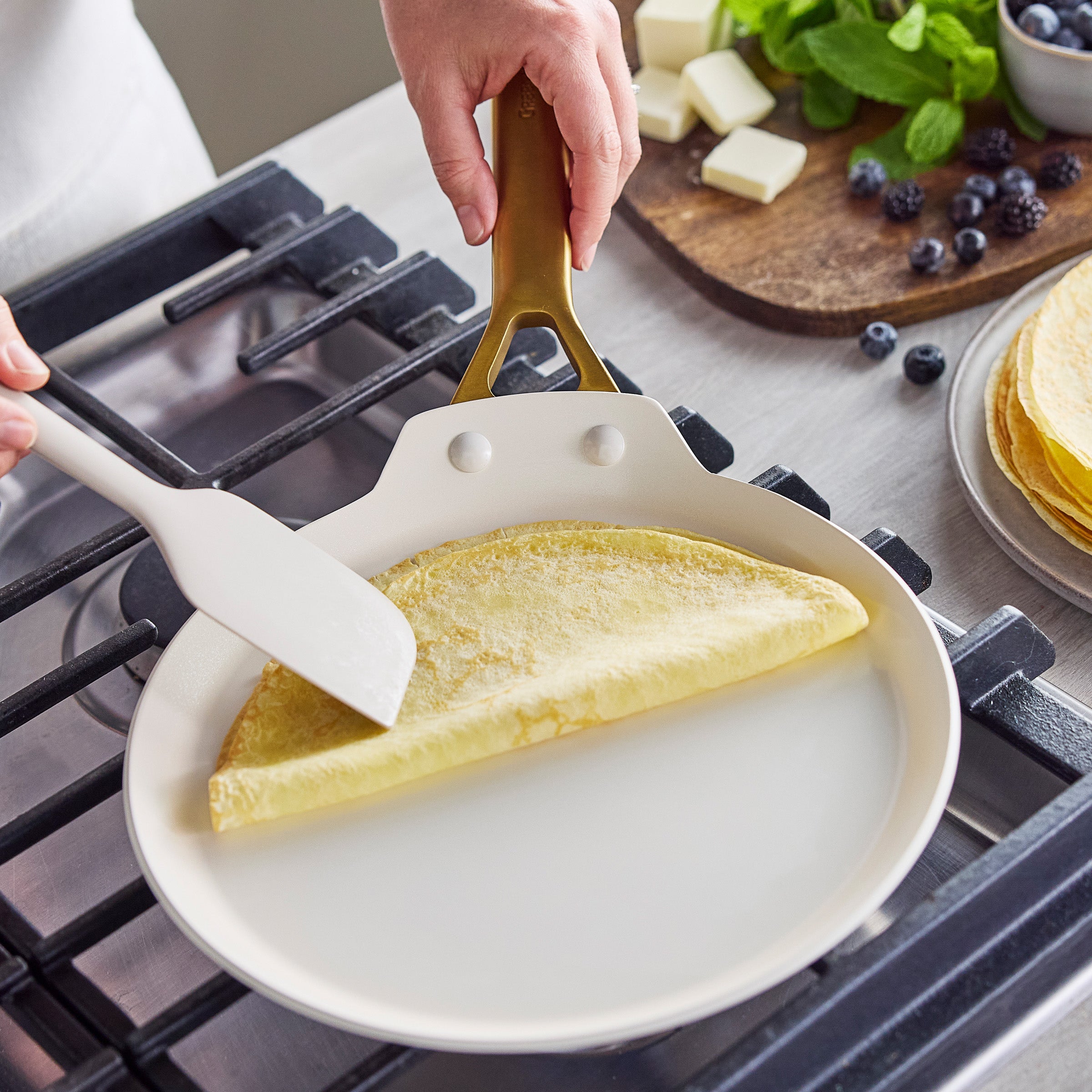 Person folding a crepe in a crepe pan on a gas stove