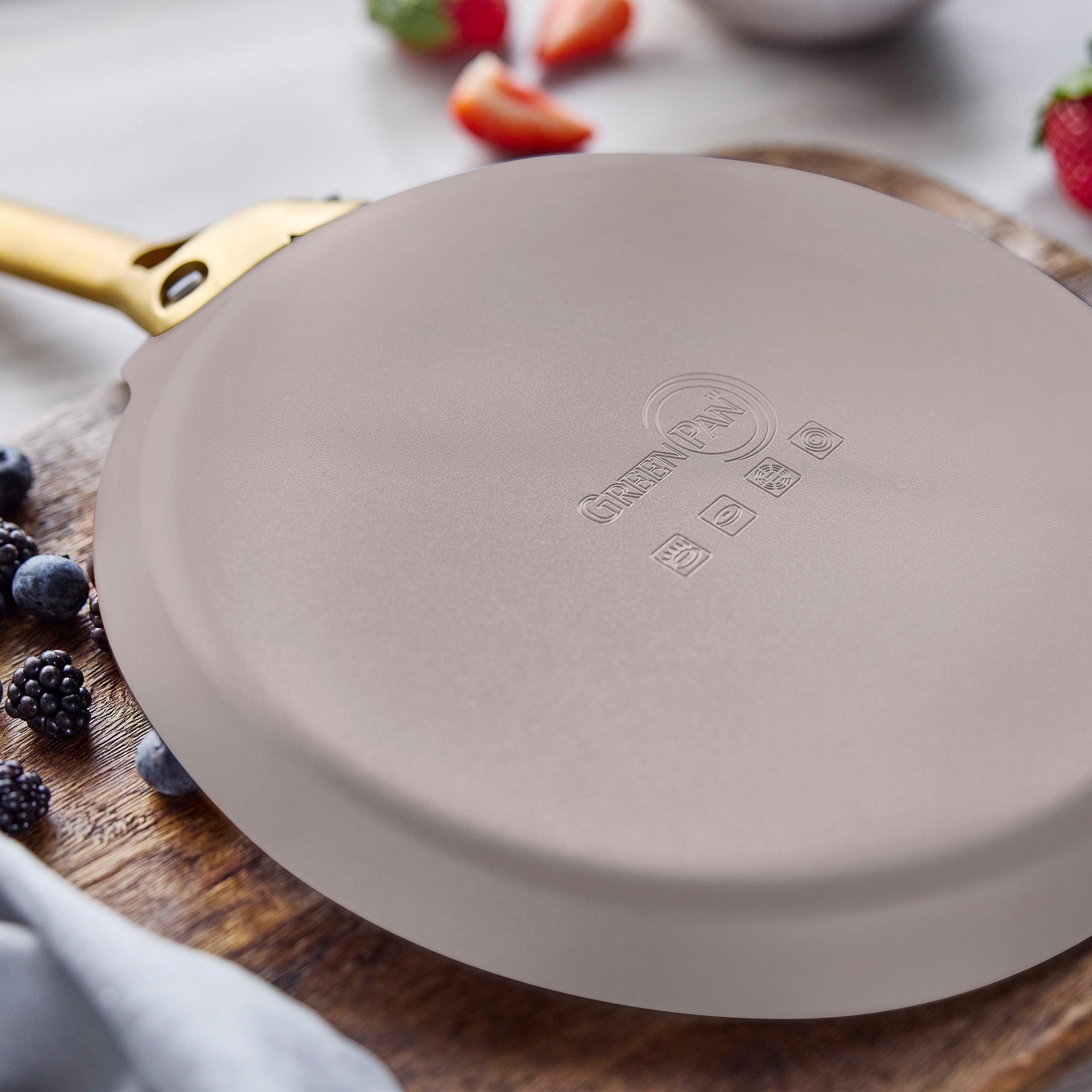 Taupe crepe pan on a wooden board with berries in the background
