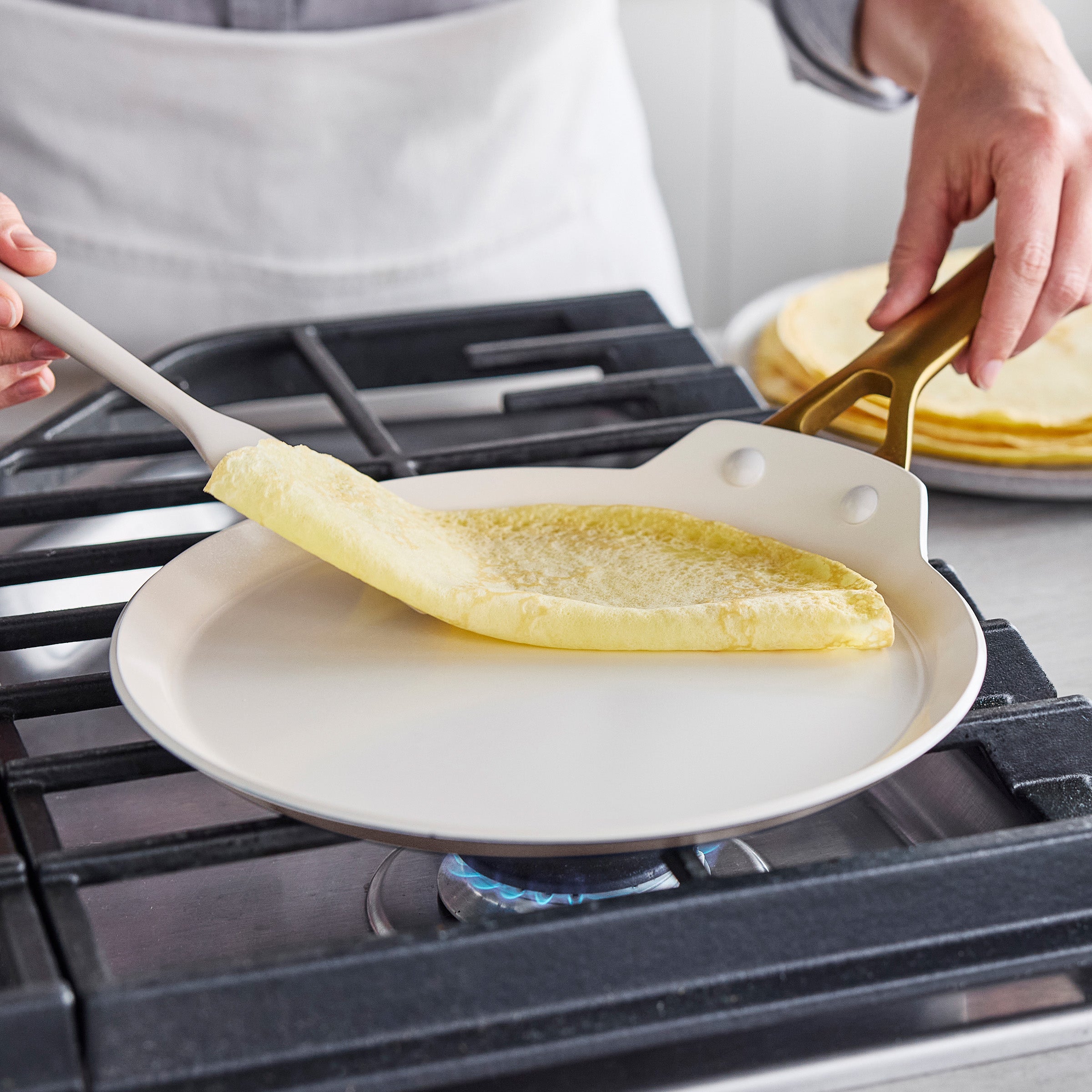 Person folding a crepe in a crepe pan on a gas stove