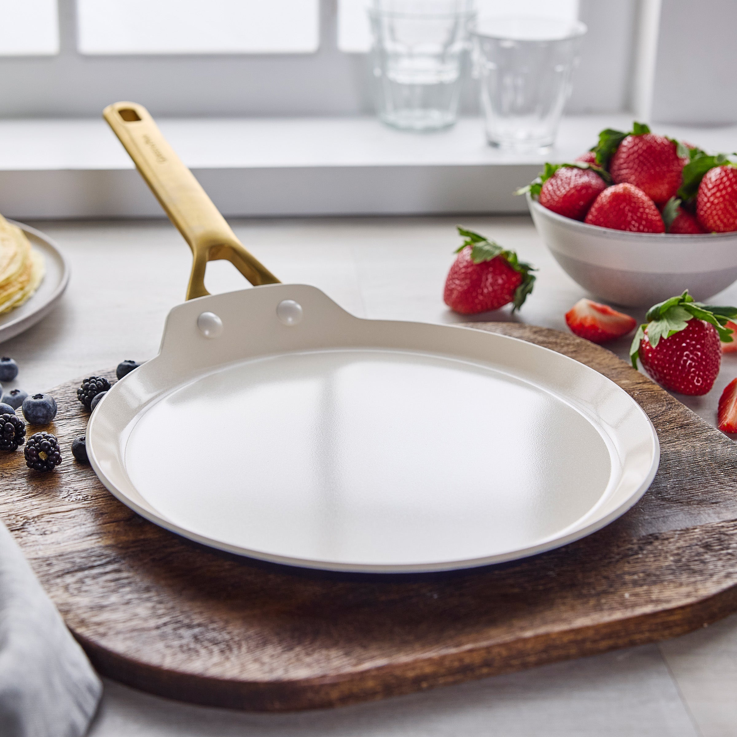 Crepe pan on wooden board with berries the background
