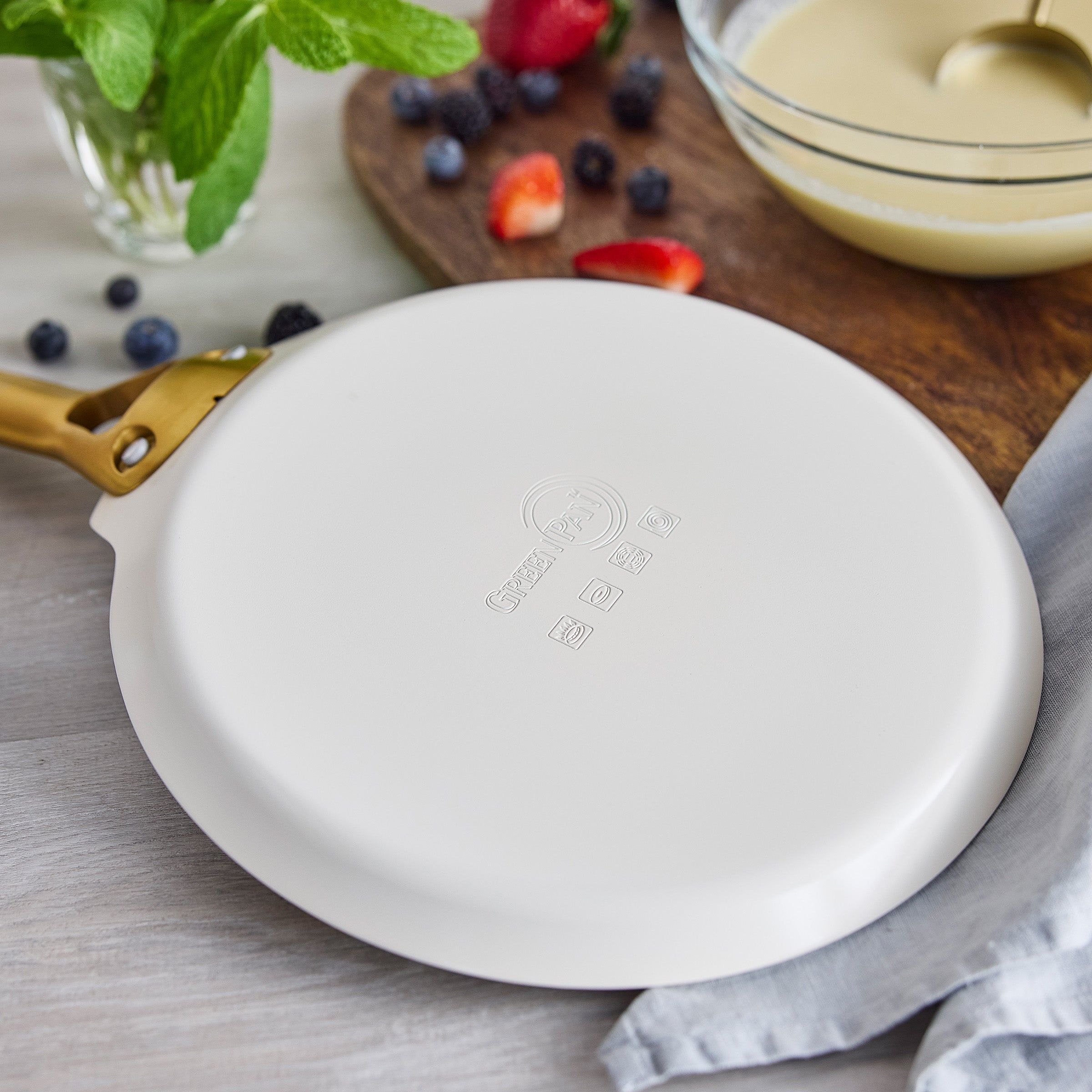Cream crepe pan on a wooden board with berries in the background
