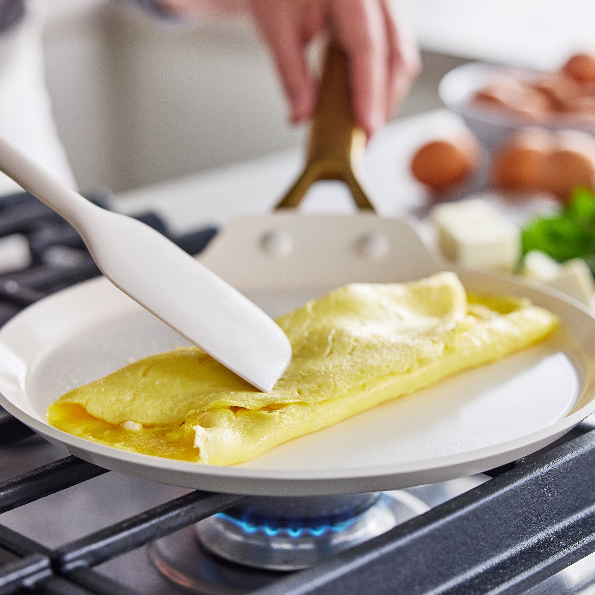 Person cooking an omelette in a crepe pan on a gas stove