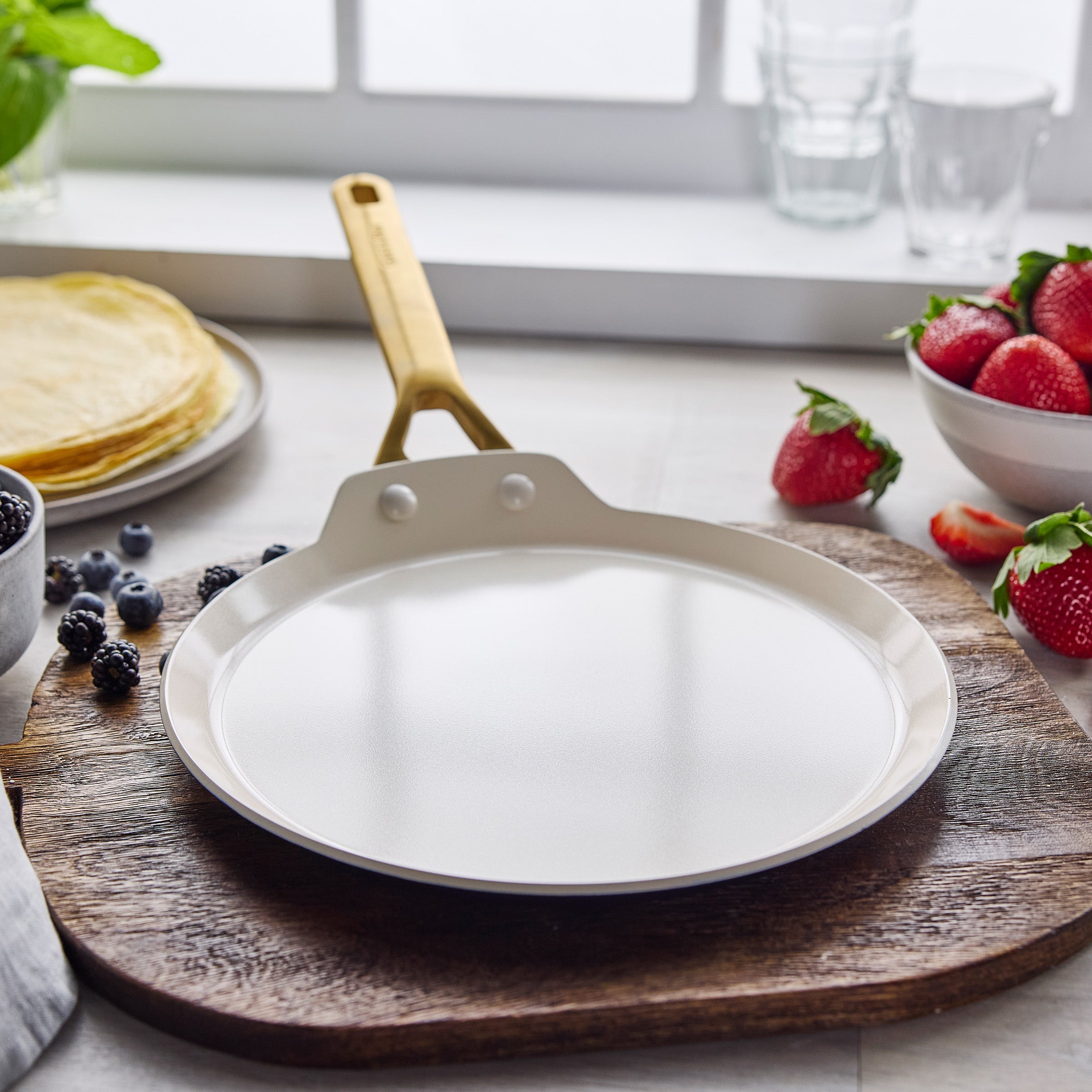 Crepe pan on wooden board with berries the background