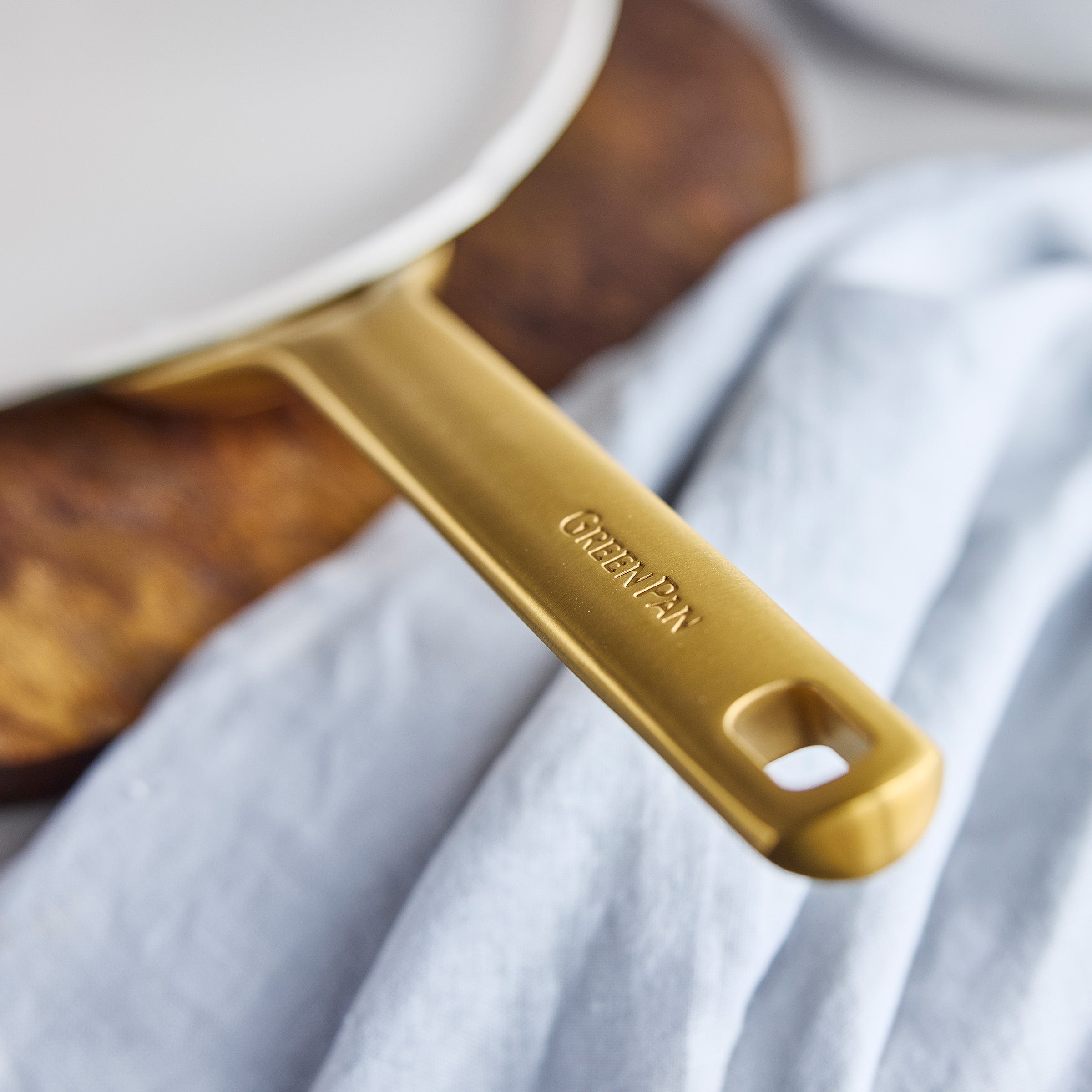 Gold-handled crepe pan on a white cloth with blurred background