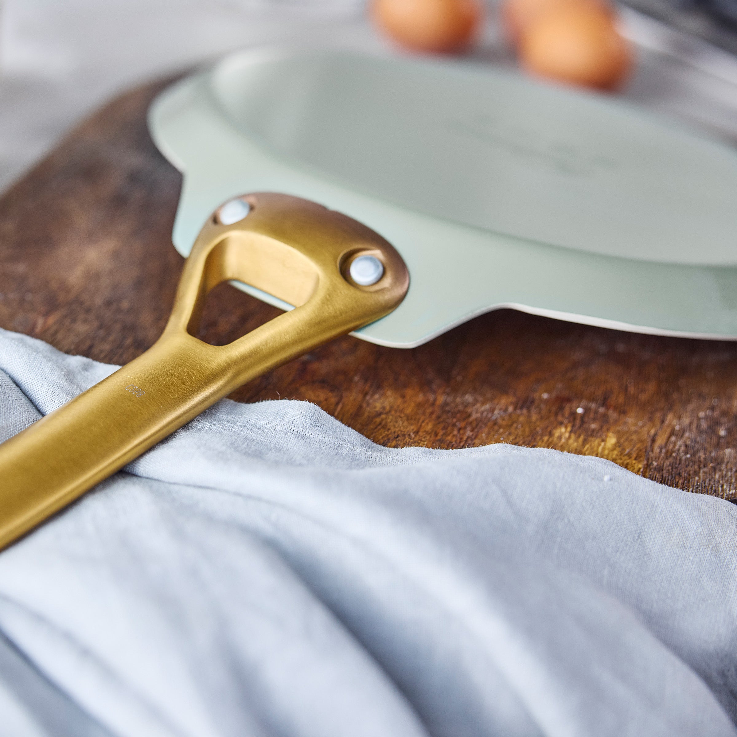 Green crepe pan with a gold handle on a wooden surface