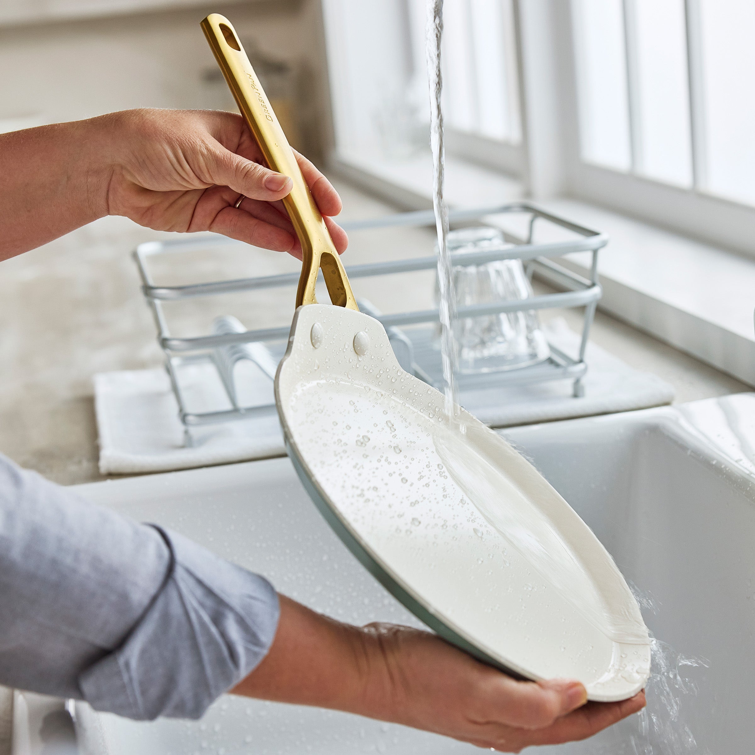 Person washing a crepe with a gold-handle in a kitchen sink.