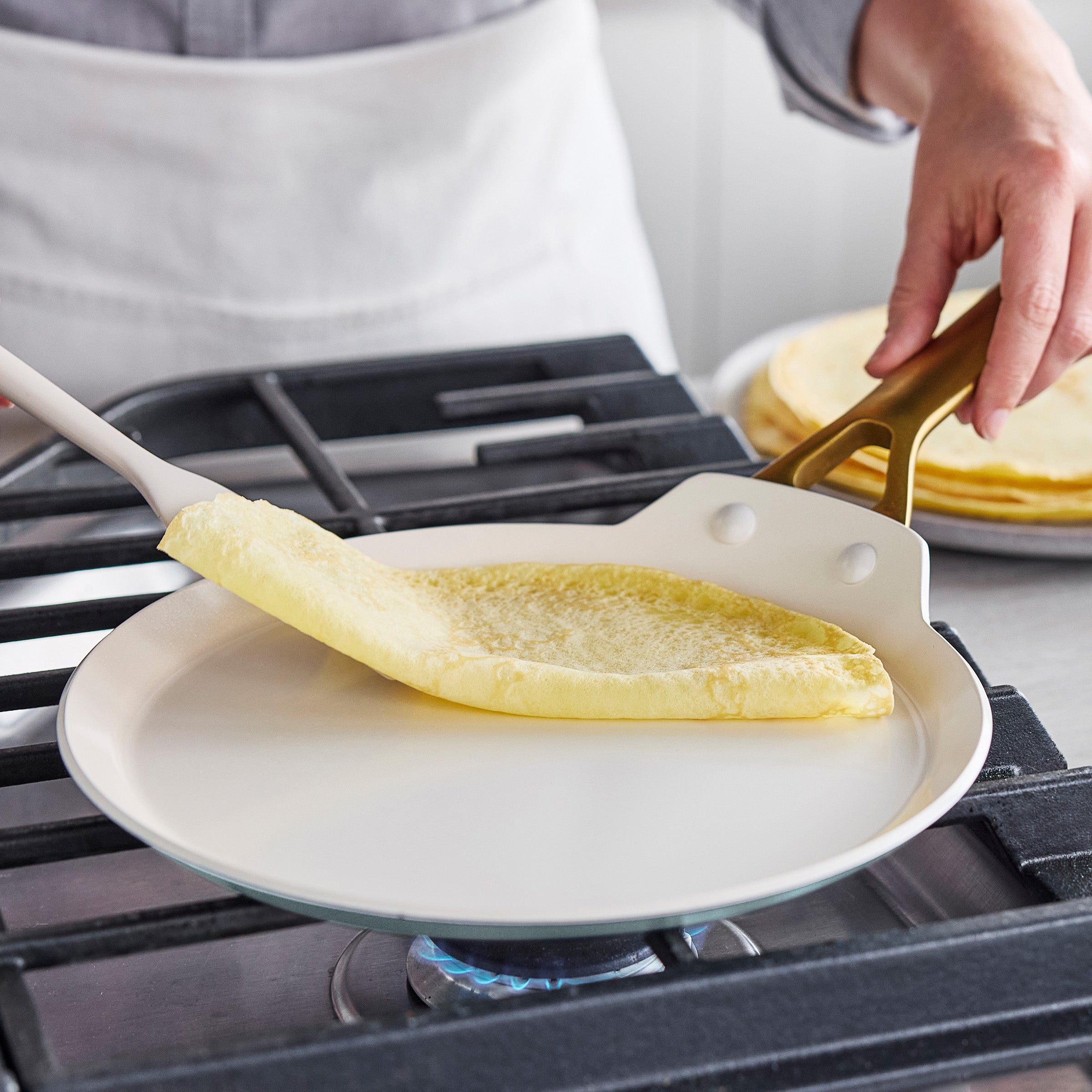 Person making crepes on a stove with a spatula
