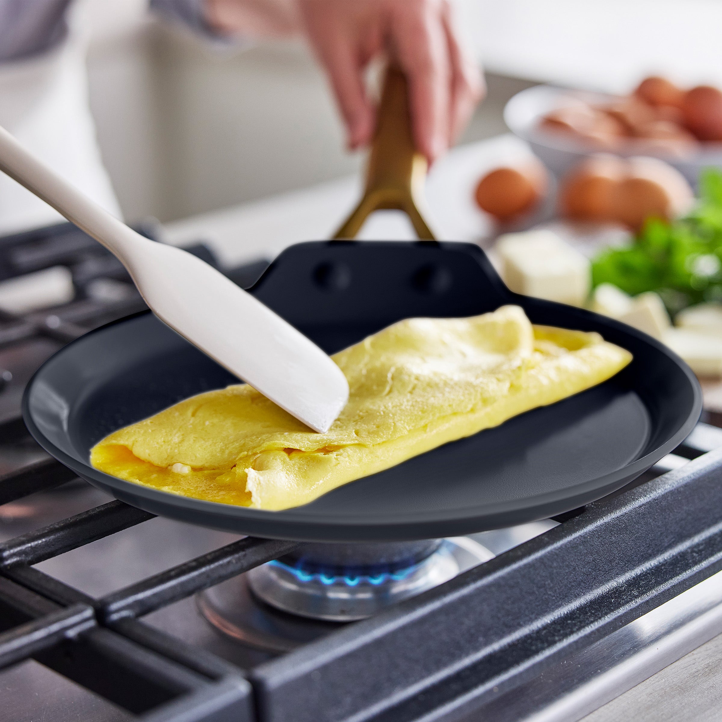 Person cooking an omelette on a gas stove using a spatula