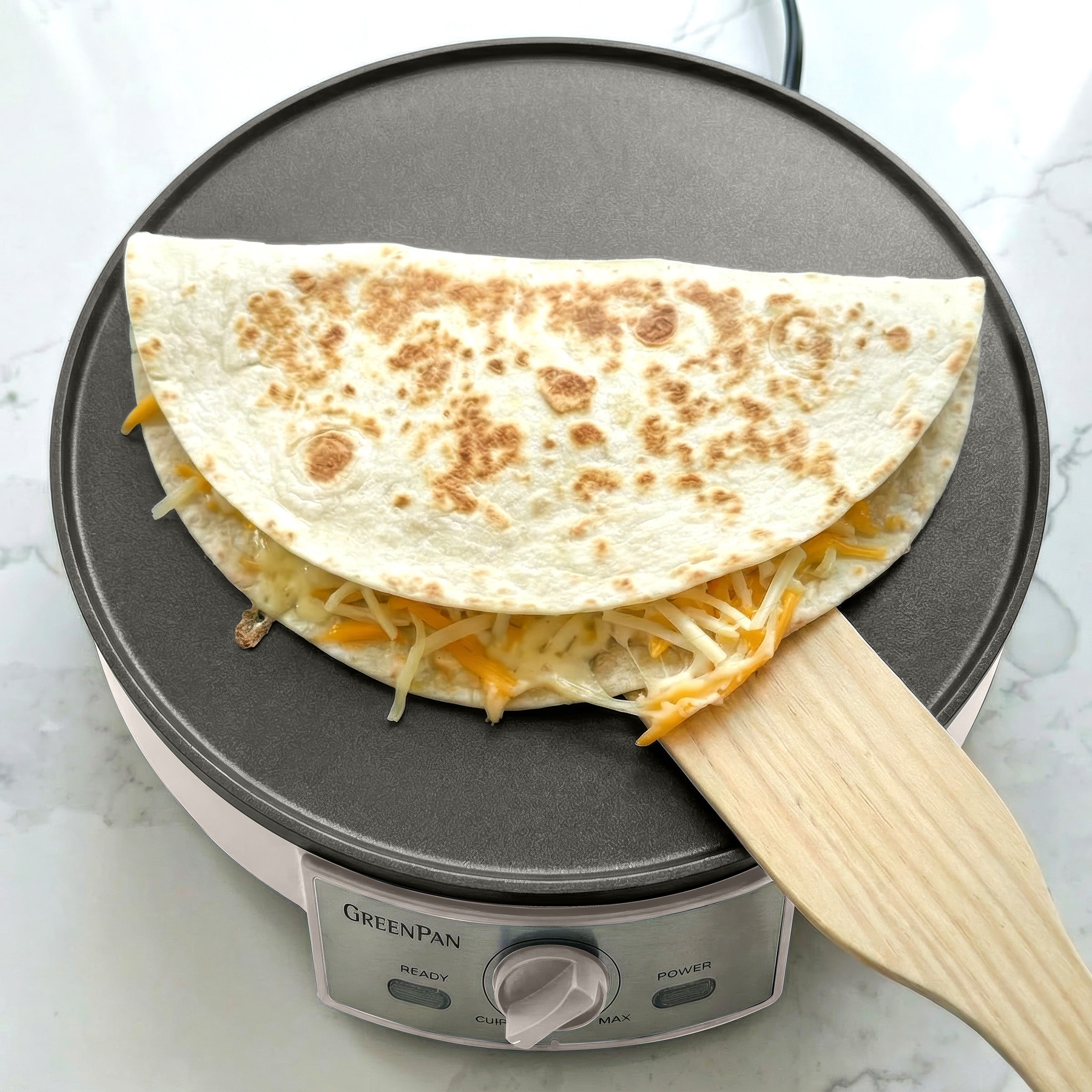 Quesadilla being made on a GreenPan crepe maker with a spatula
