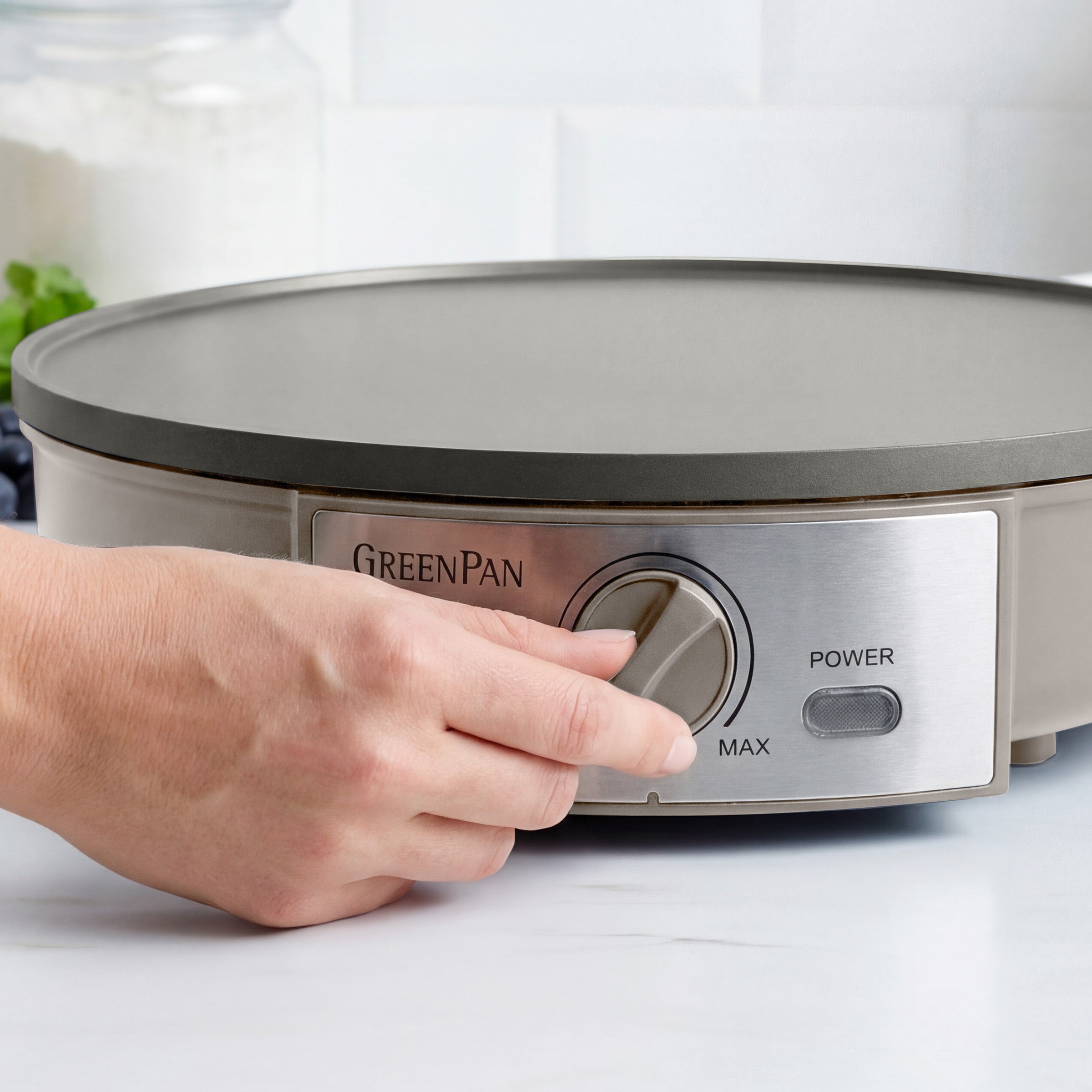 Hand adjusting the knob on a GreenPan electric crepe maker.