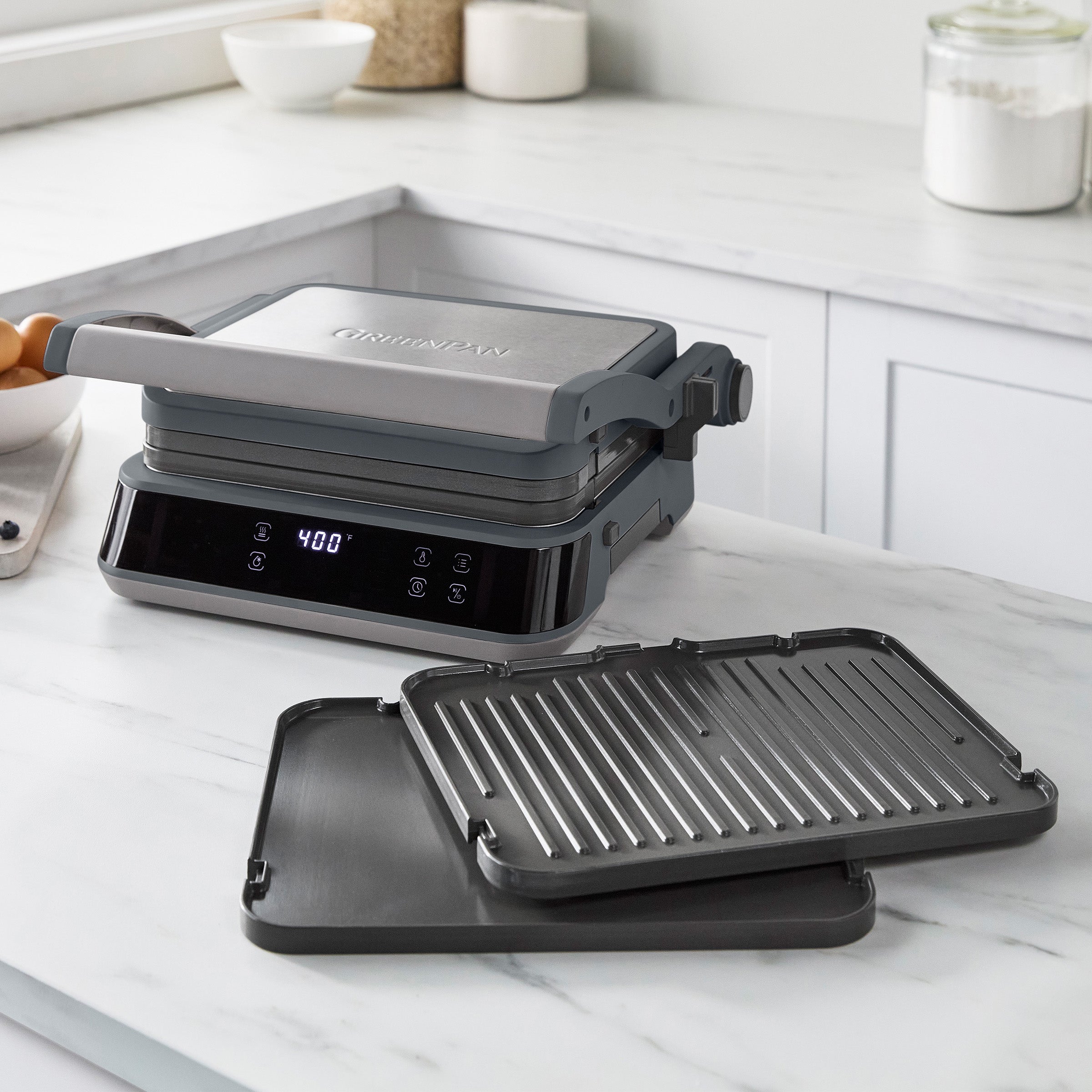 Graphite grill and griddle on a marble countertop with ceramic plates removed and placed in front.
