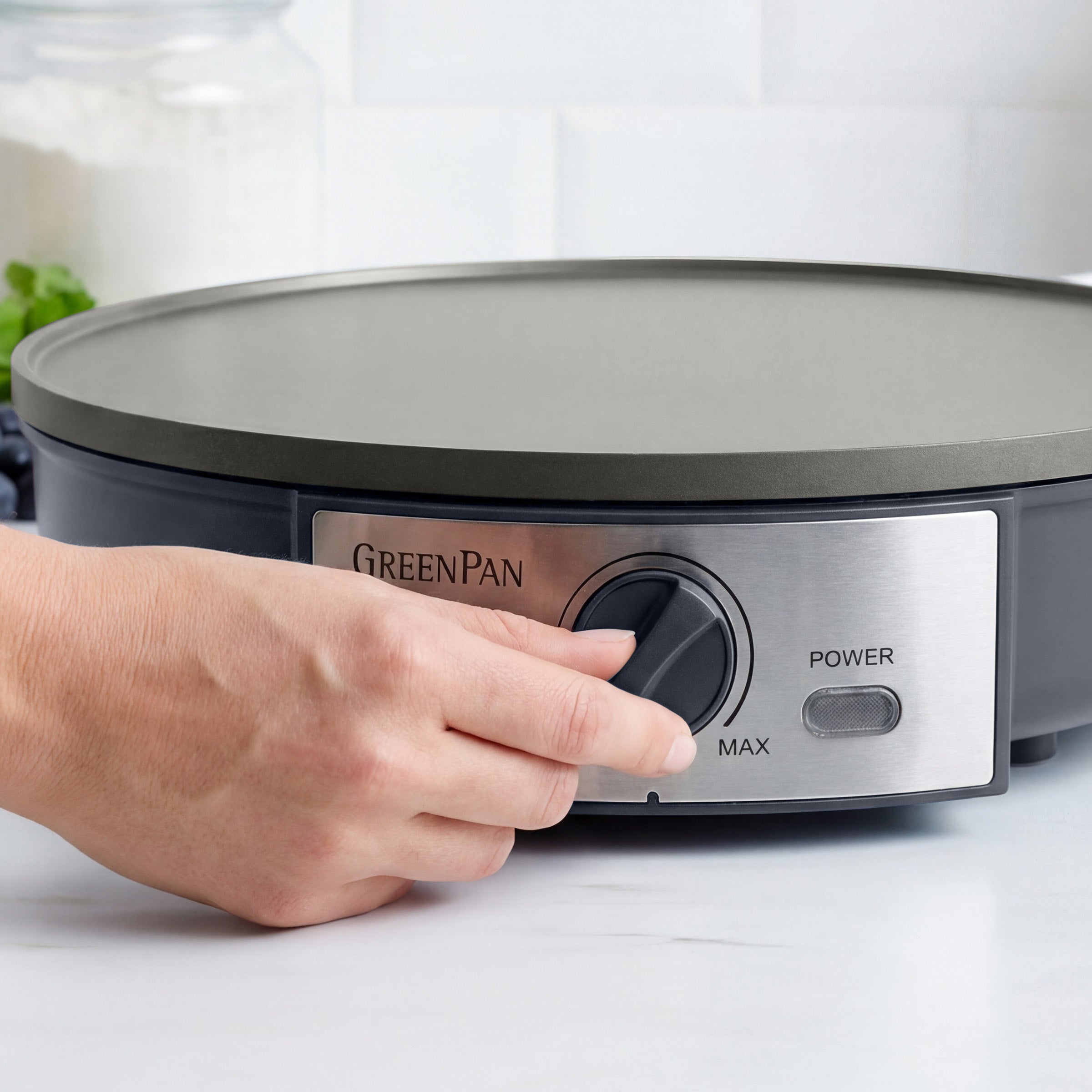 Hand adjusting the knob on a GreenPan electric crepe maker.