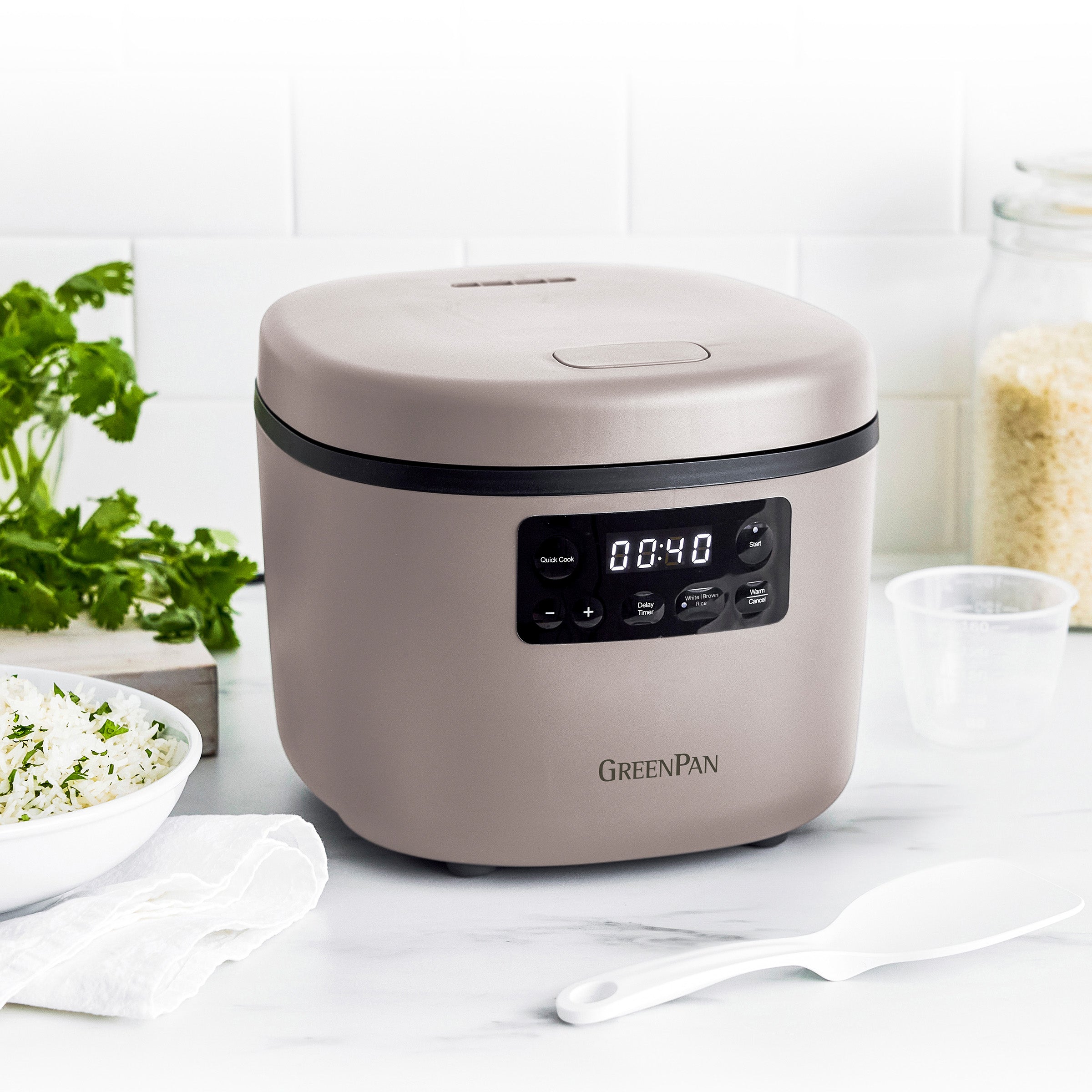 Taupe rice cooker with digital display on a kitchen counter, featuring the GreenPan brand.