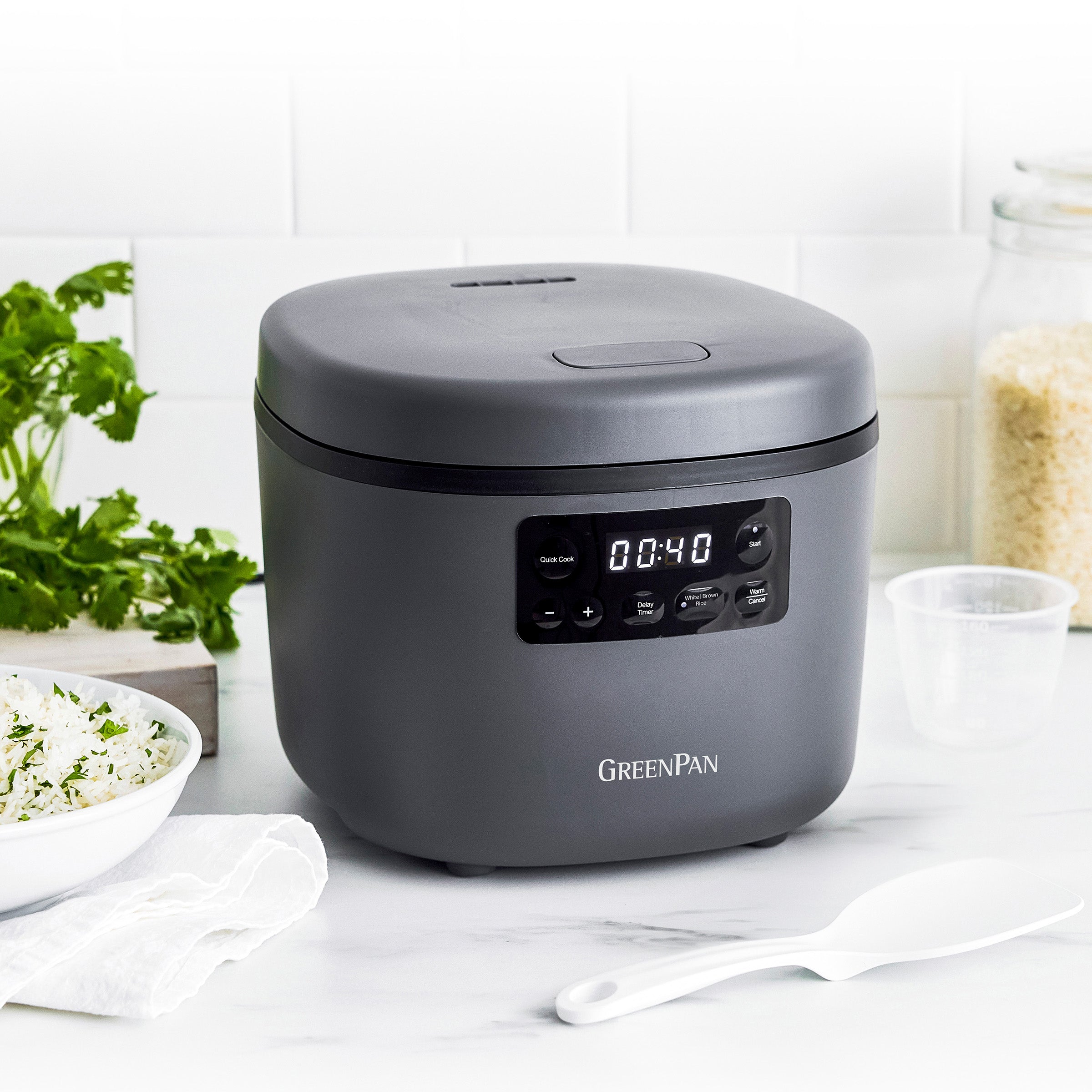 Gray GreenPan rice cooker on a kitchen counter with ingredients in the background