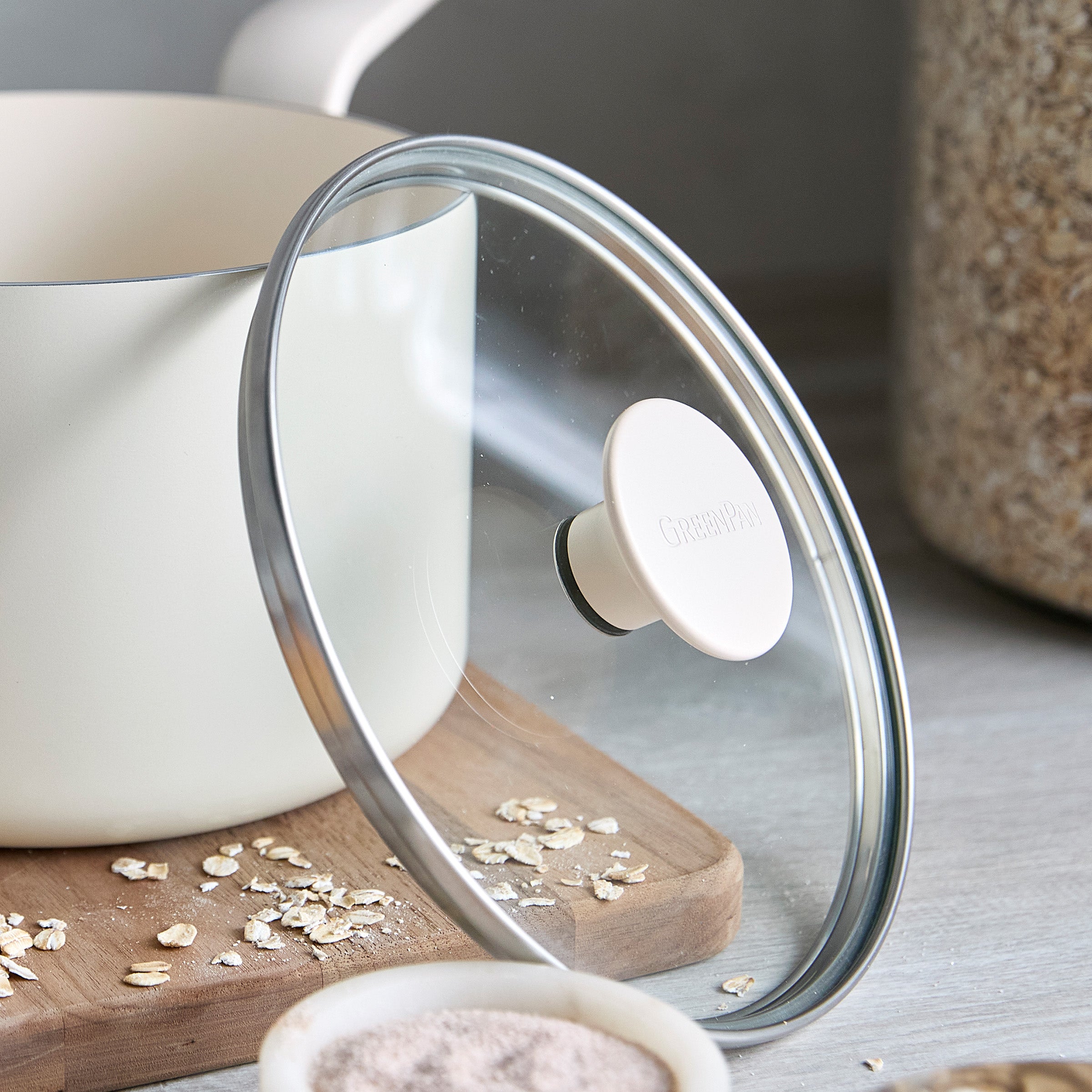 Ceramic nonstick saucepan with lid, light blue, 2-quart size, on a counter next to oats, grains, and a wooden board.
