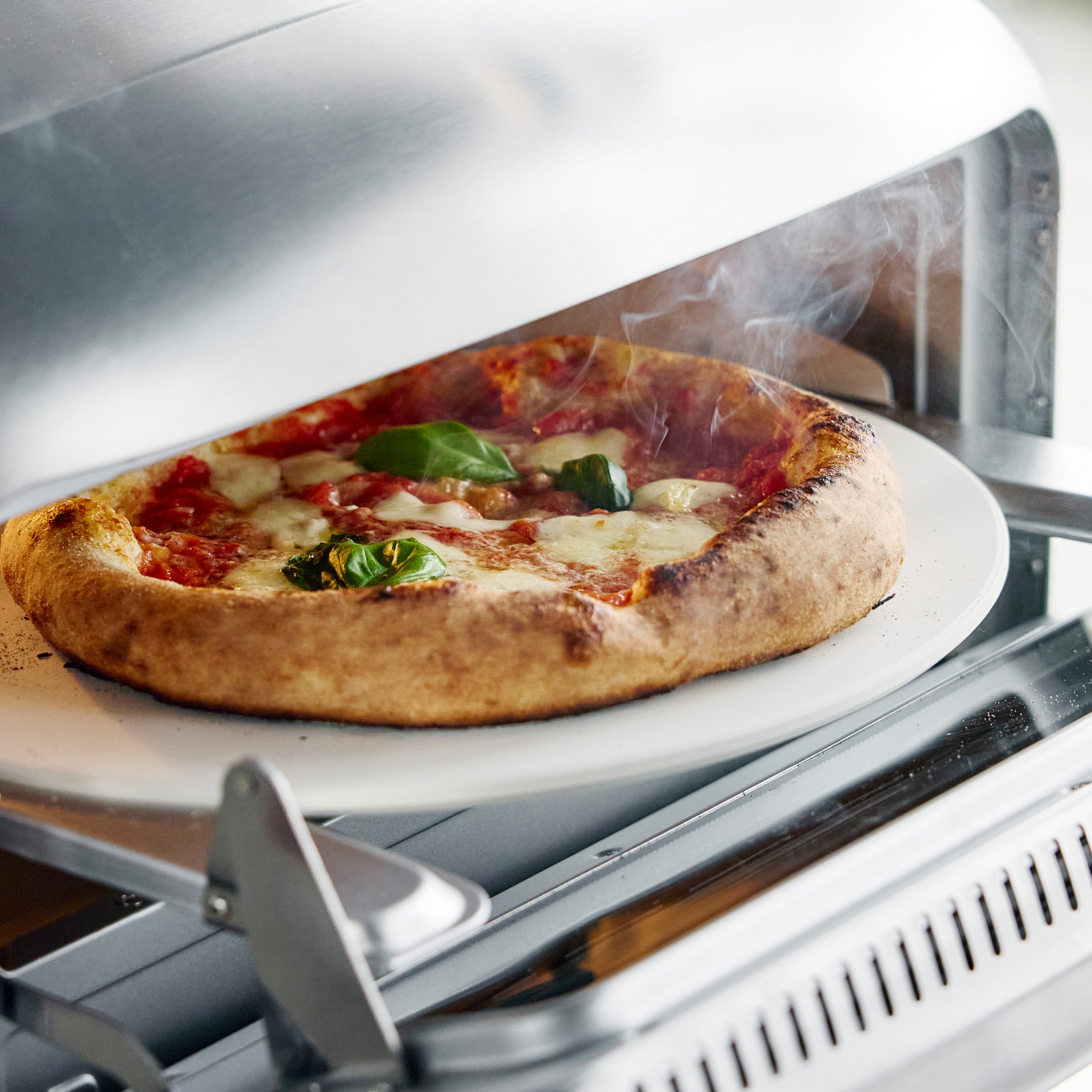 Stainless steel pizza oven with a pizza on a pizza stone inside