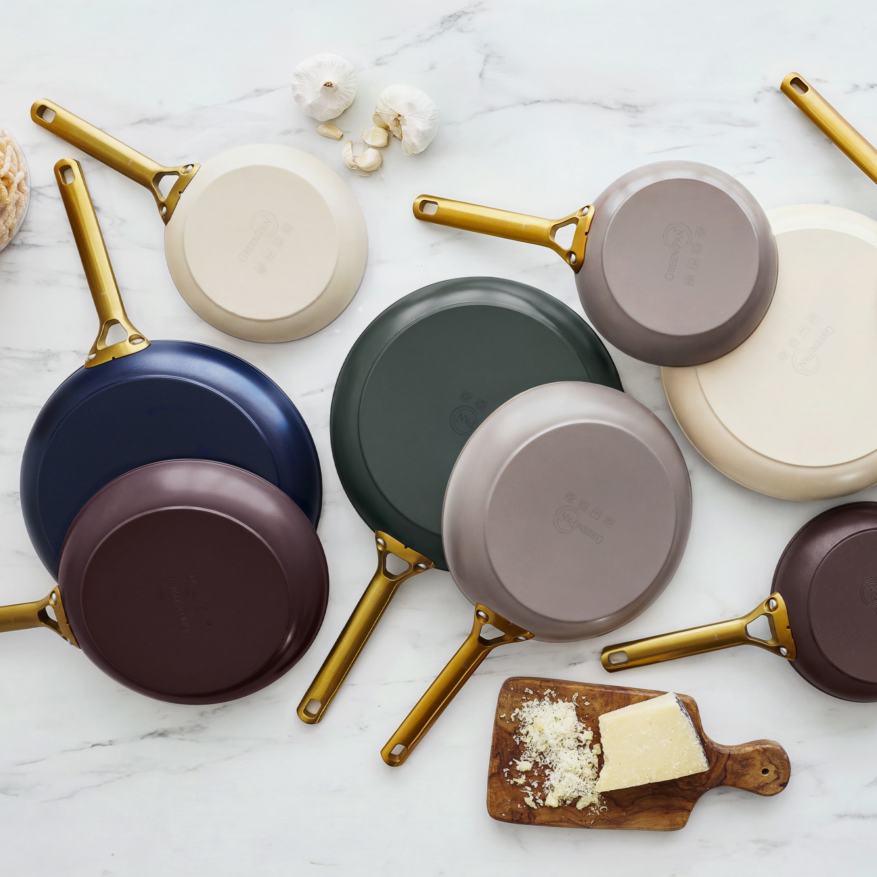 Spruce green ceramic 8-inch frypan with gold handle on marble, surrounded by cheese, garlic, and mushrooms.