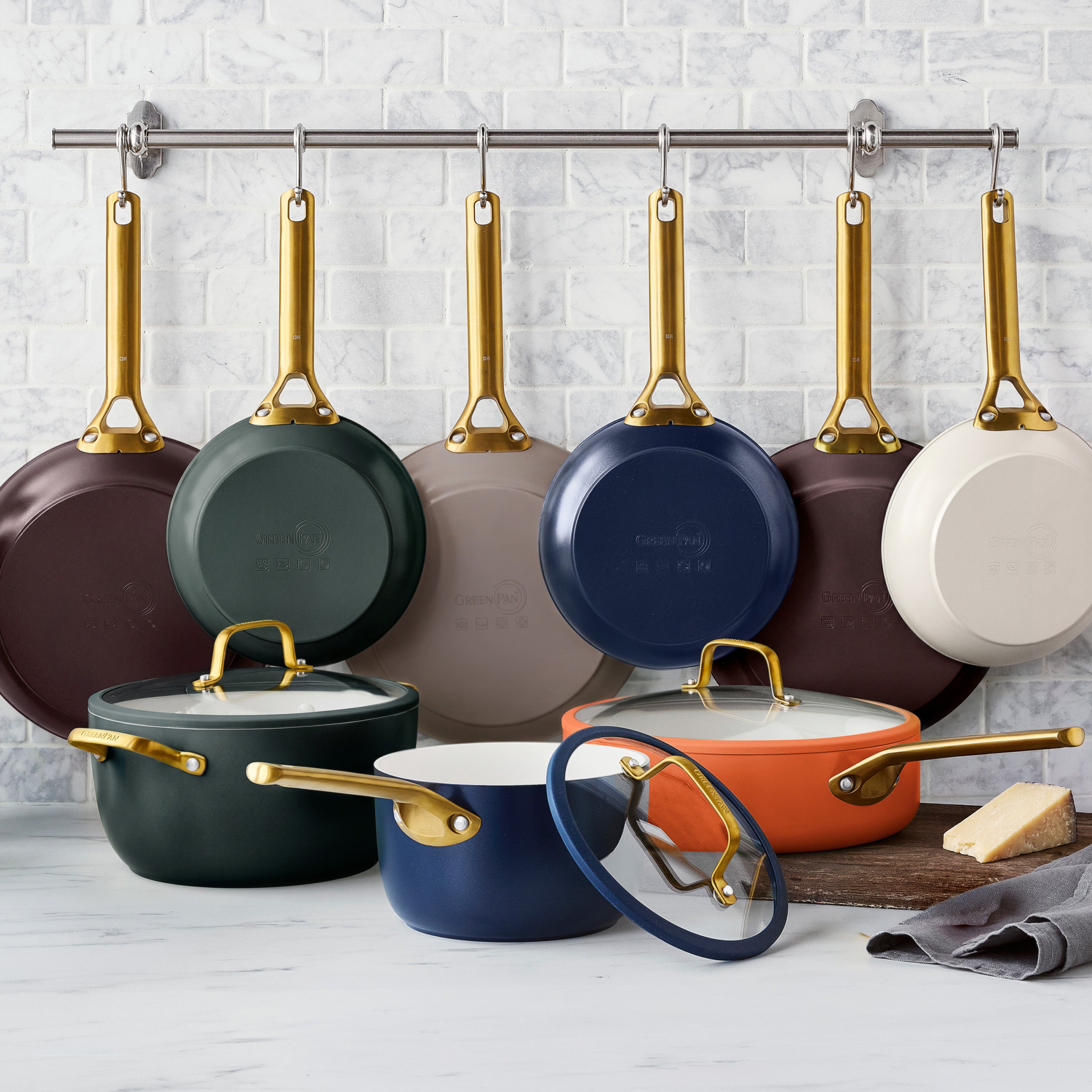 Ceramic nonstick 10-piece cookware set in spruce green with gold handles, stackable on a white countertop.