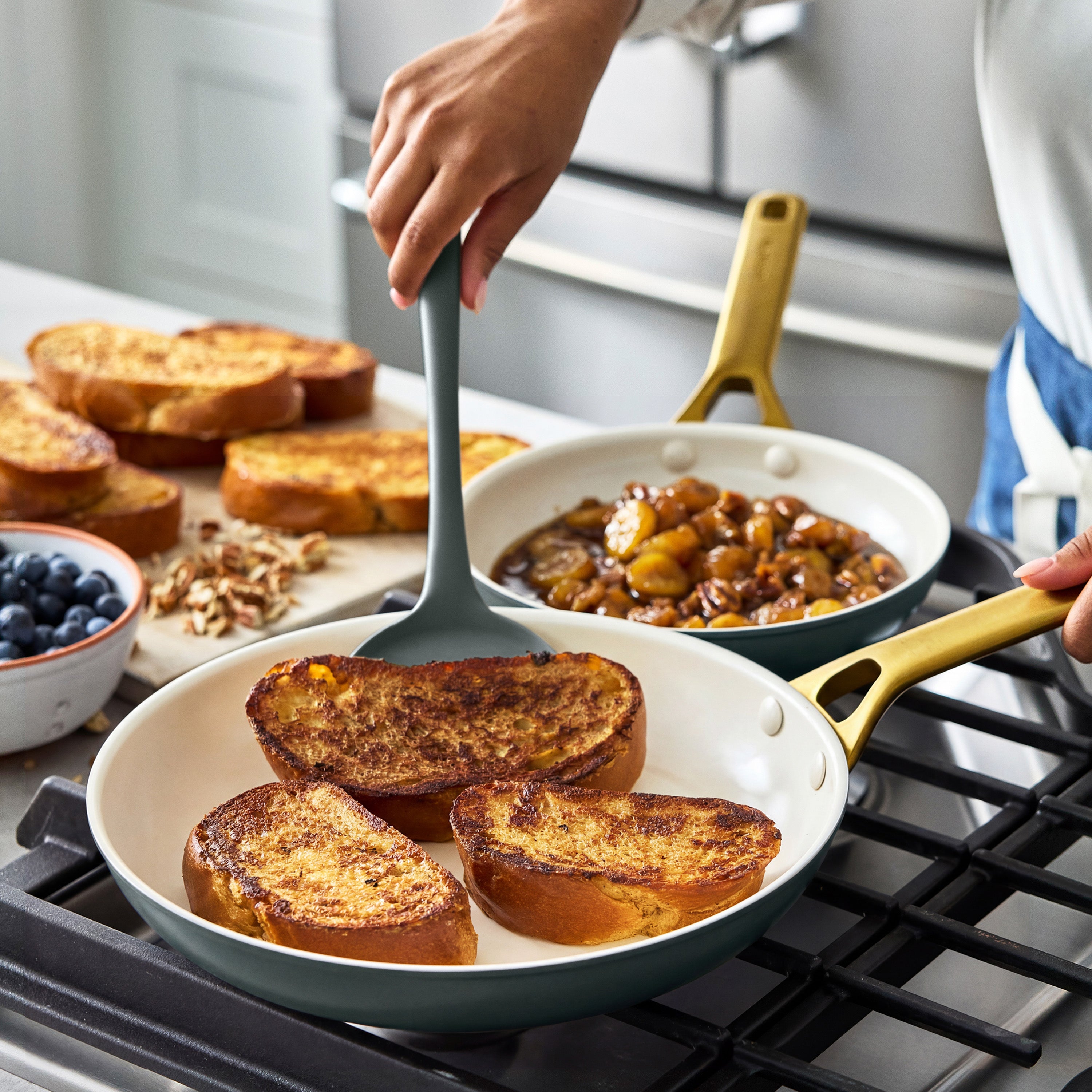 Cooking French toast with caramelized fruit in a ceramic nonstick cookware set, 10-piece, black.