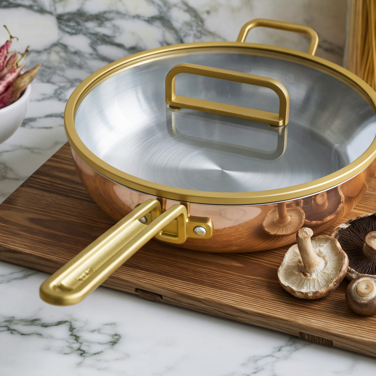 Copper 4.5-quart pan with lid on a board beside fresh mushrooms on a marble countertop.